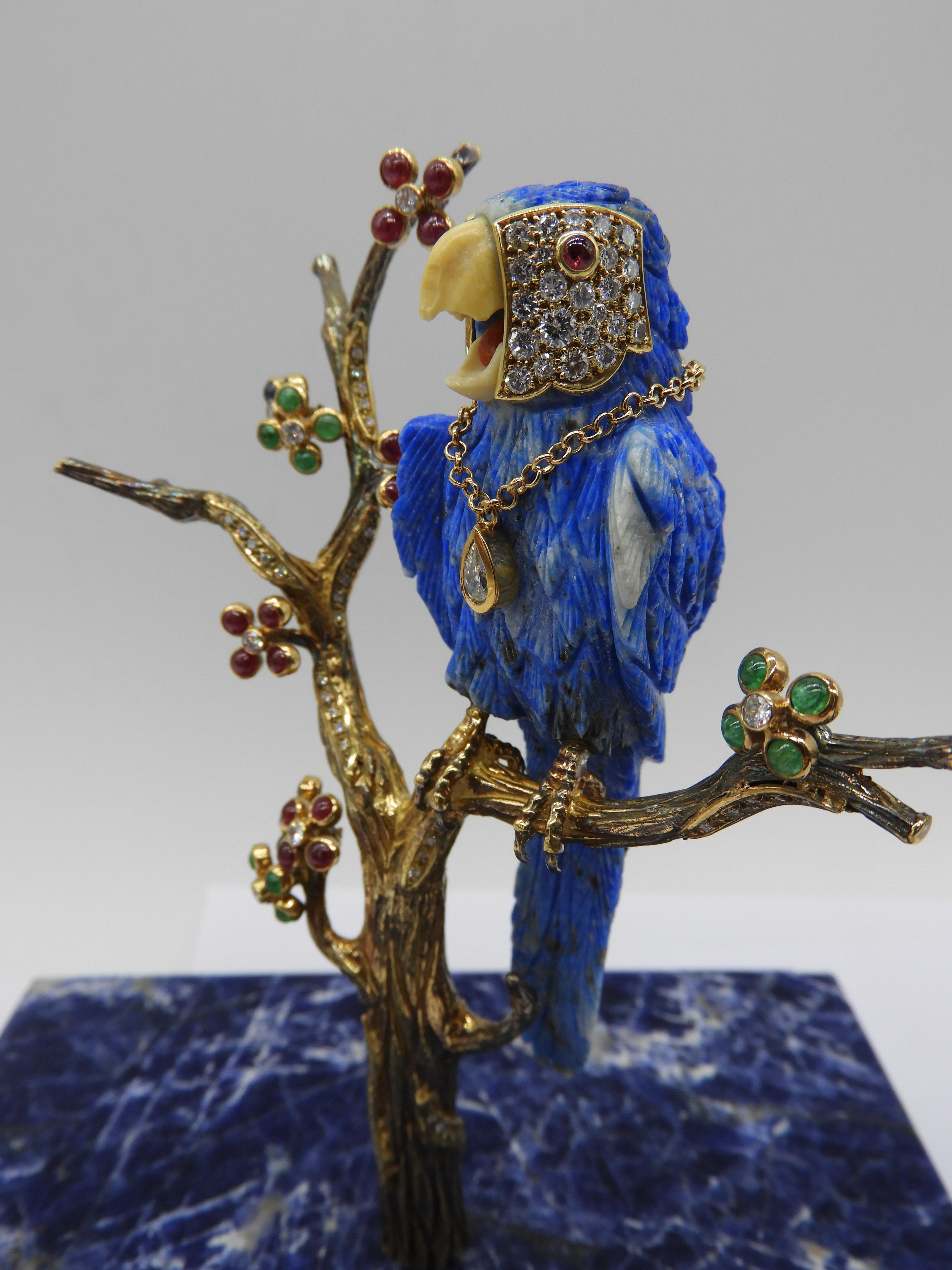 Beautiful happy and vibrant macaw in 18k gold, diamonds and lapislazuli stone standing on a branch tree made of 18k gold 
Branch tree is adorned with yellow gold, diamonds, rubies, saphires, emeralds all cabouchon cut
And the Macaw is defined with a