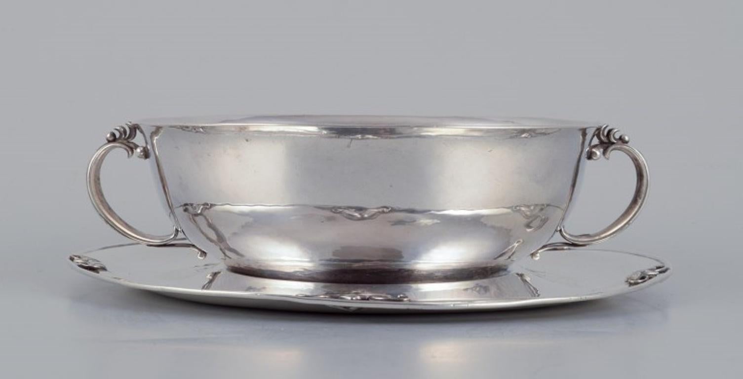 Harald Nielsen for Georg Jensen. Sterling silver bowl with handles on a matching saucer.
Georg Jensen hallmark and Swedish import hallmark on both the bowl and saucer.
Model: 456
1920s.
In excellent used condition.
Bowl: Diameter 13.3 cm without