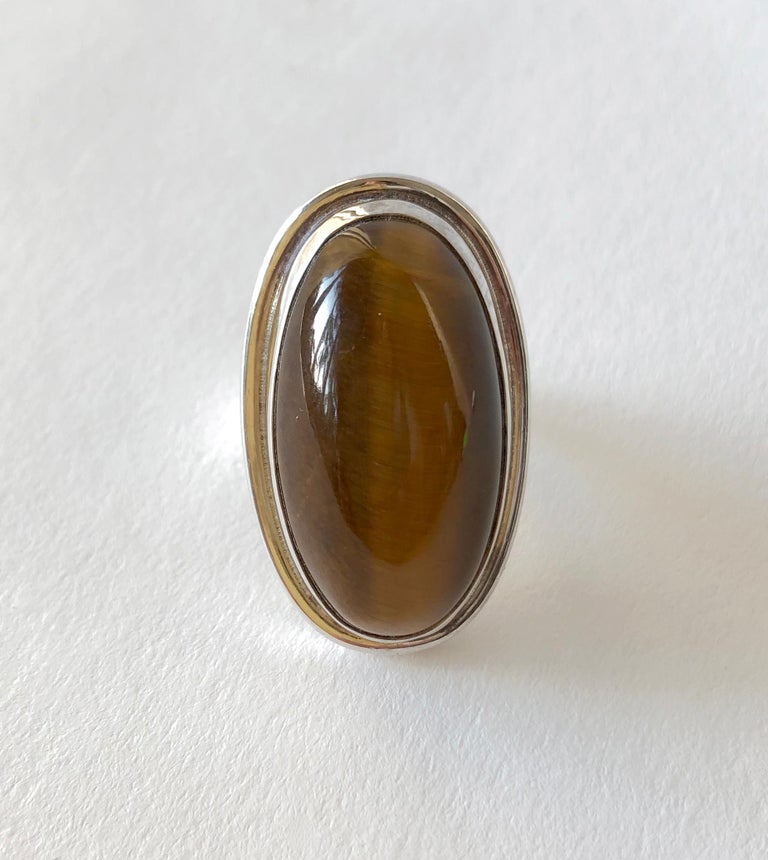 Sterling silver ring set with a large, golden tiger's eye cabochon stone designed by Harald Christian Nielsen for Georg Jensen, circa 1950.  Ring is a finger size 7 and is signed Georg Jensen, 46E, Denmark. In very good vintage condition.

Neilsen