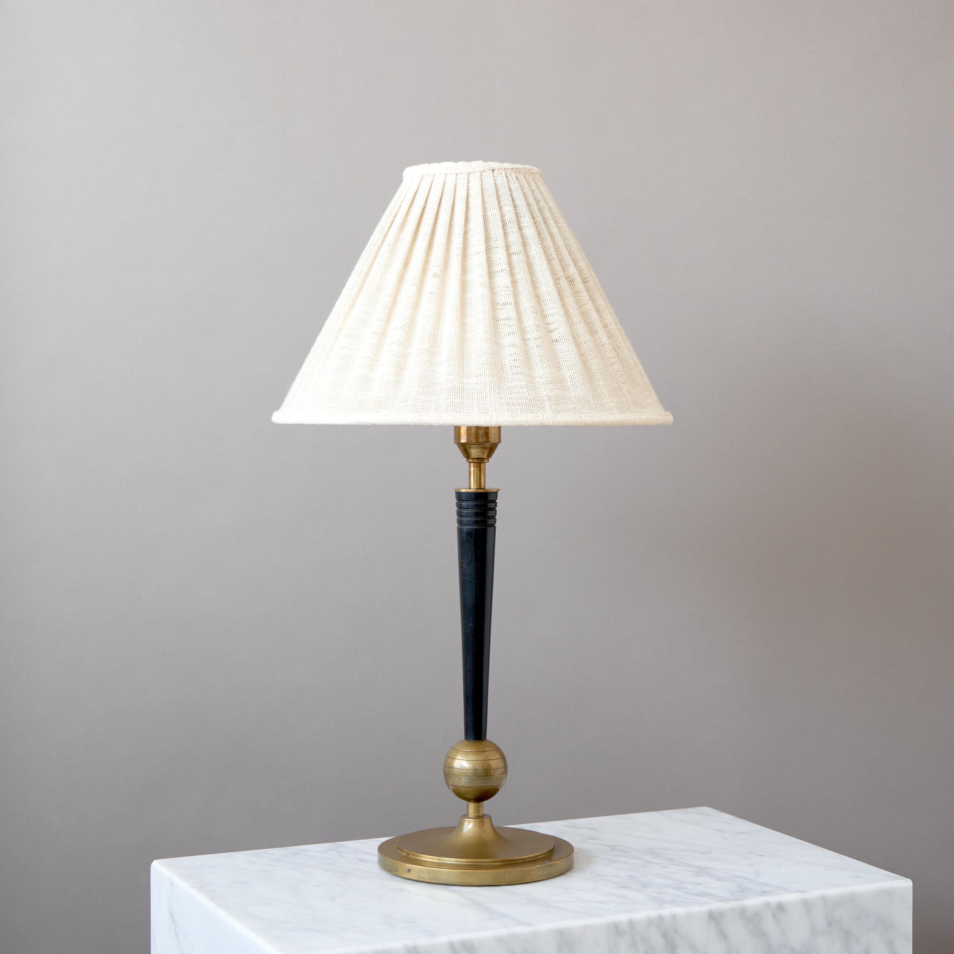 An elegant Art Deco / Swedish Grace brass and wood table lamp.
Designed by Harald Notini for Böhlmarks, Sweden, 1930s.

Great original condition with amazing patina.
Sold without lampshade.

Dimensions of the lamp (without the shade):
Height (incl.