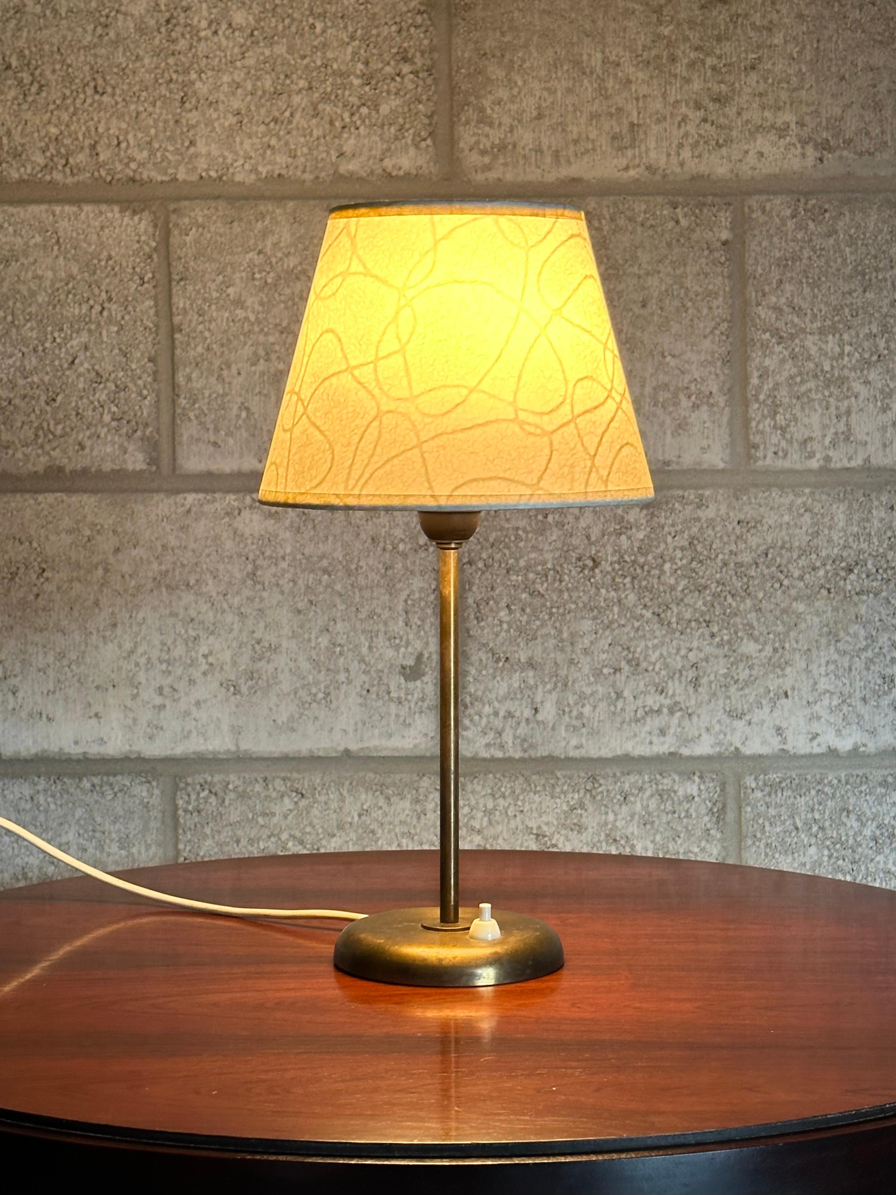 A gorgeous minimalist table lamp attributed to Harald Notini for Böhlmarks. Features a weighted brass base with slender body and complete with a simple shade. A great desk or nightstand lamp which has subtle character and warmth. 

Overall:
15