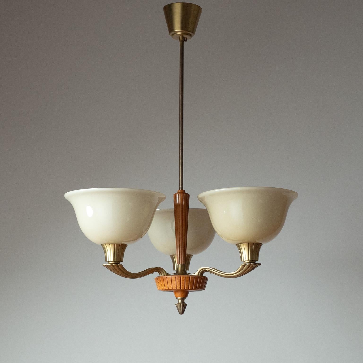 Raro lampadario Art Deco Böhlmarks degli anni 1930-1940, progettato da Harald Notini. Centrotavola e decorazione a stelo in legno di olmo a coste, con tre bracci in ottone fuso, ciascuno con un diffusore in vetro soffiato color avorio. In buone