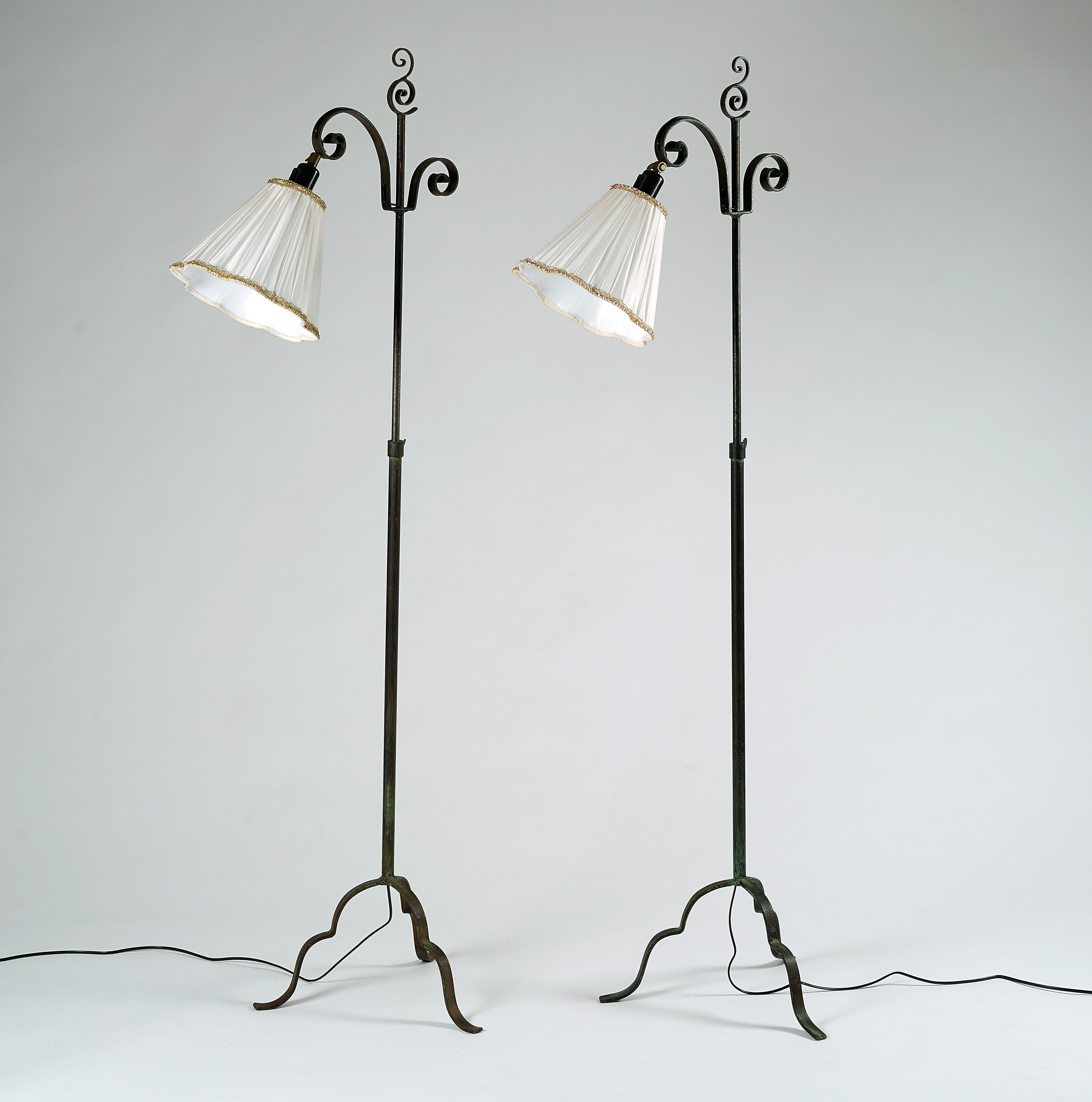 Ein Paar verstellbare Stehlampen aus patiniertem Schmiedeeisen. Entworfen von Harald Notini für Arvid Böhlmarks Lampfabrik in den 1930er Jahren. Modell 15101. Neue Schattierungen in weißem Stoff enthalten. 

Das Eisen hat eine schöne Patina aufgrund