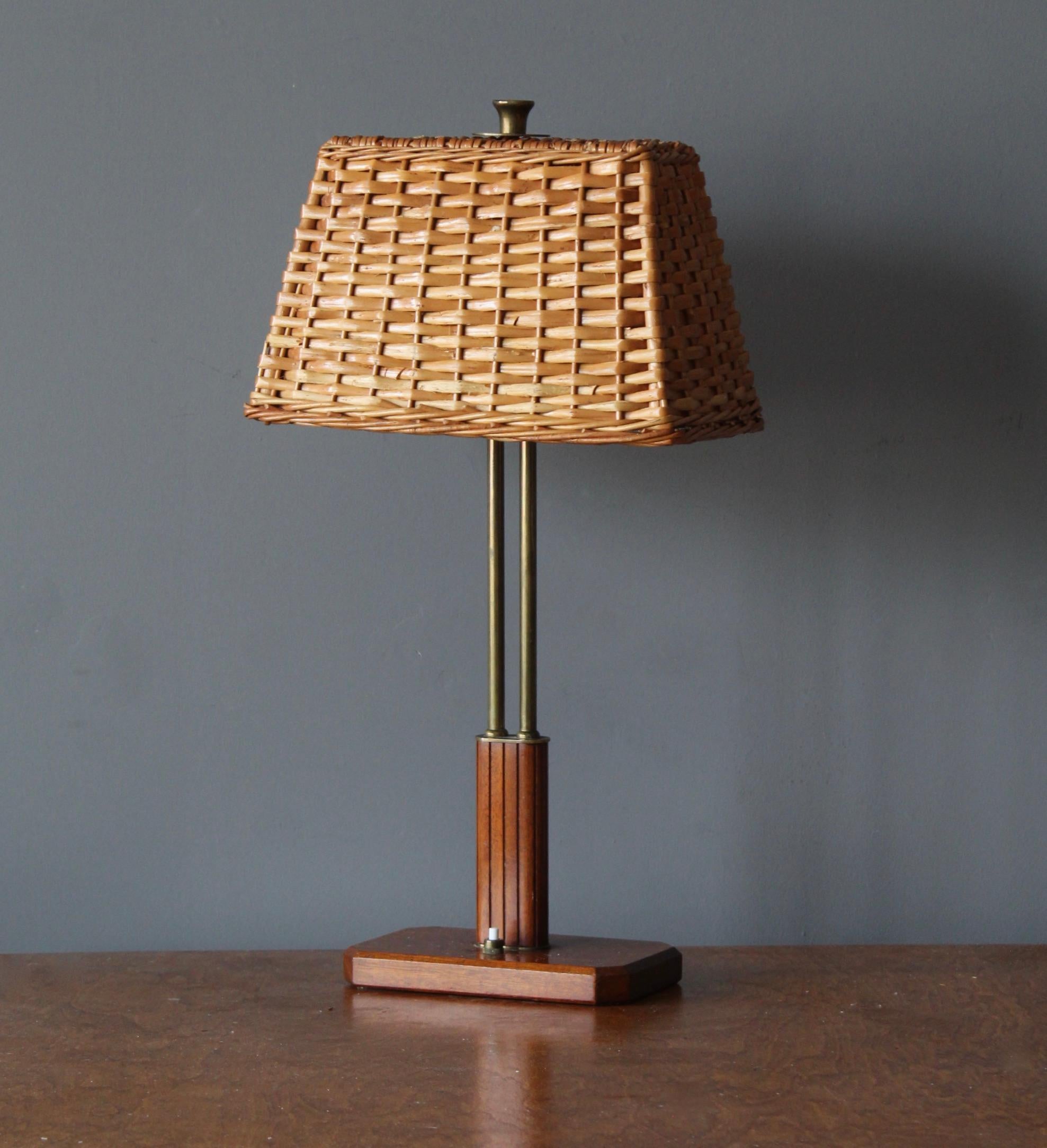 A table lamp. Designed by Harald Notini. Manufactured by Böhlmarks Lampfabrik, Sweden, 1940s. Brass, fluted mahogany. Assorted vintage rattan lampshade with original mounting hardware.

Other designers of the period include Paavo Tynell, Josef