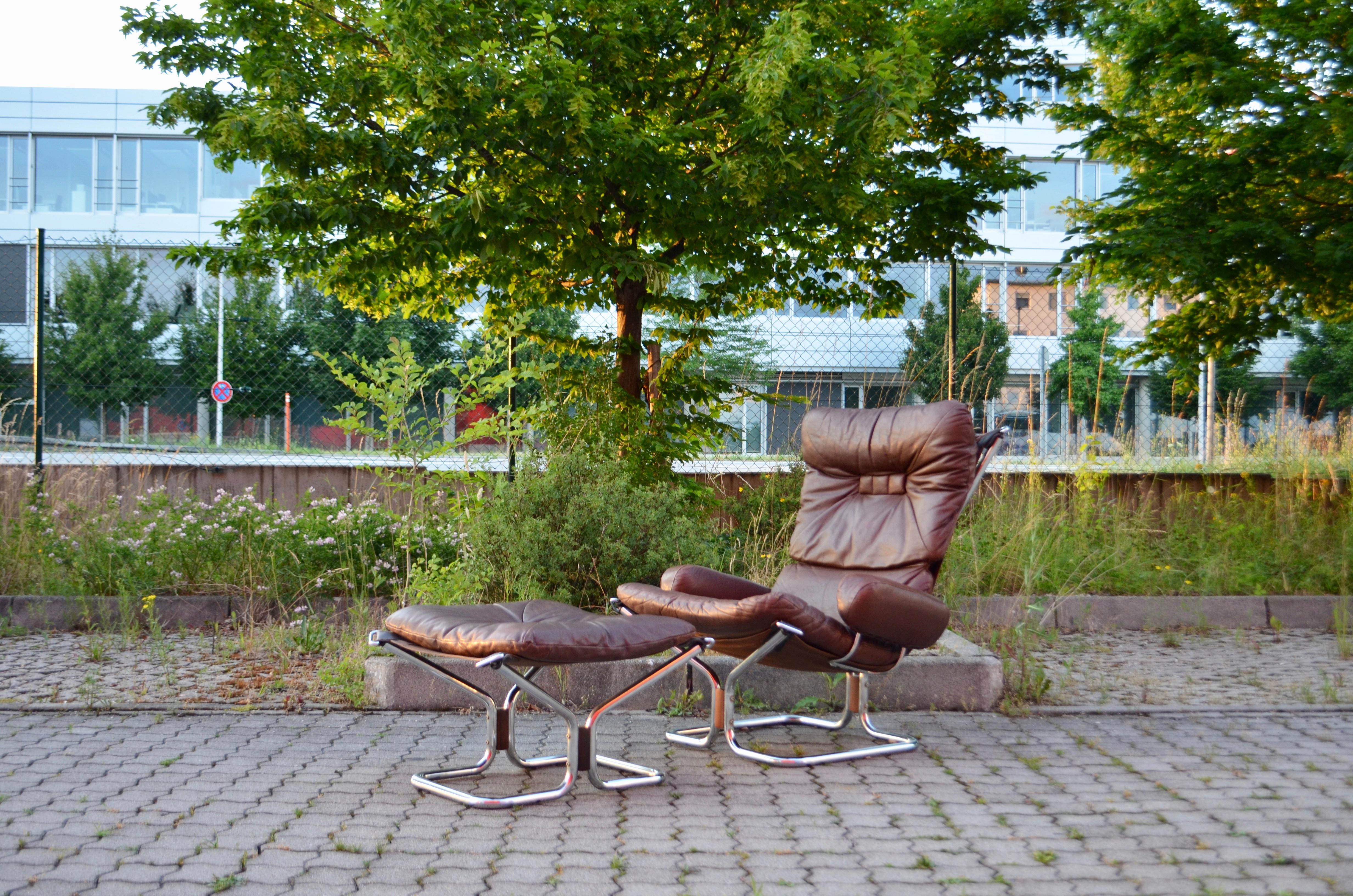 This 'Wing Wingback lounge chair and ottomane were designed by Harald Relling and were produced by Westnofa in Norway.
They are made from brown aniline leather on chromed tubular steel frame and canvas.
The loose soft pad cushions reates a