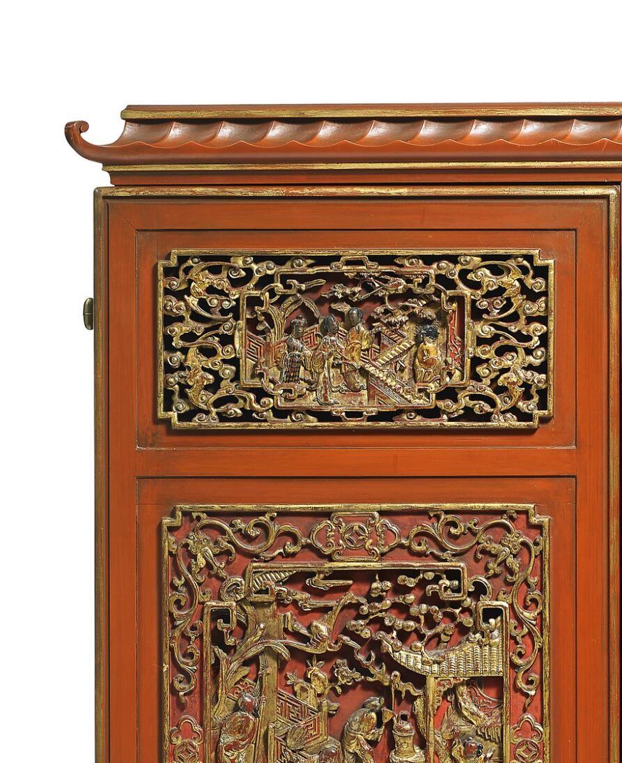 A red lacquered “Swedish Grace” à la Chinoise bar cabinet, carved with profiles painted in gold. Front with pull-out leaf and two doors, behind which shelves. Doors decorated with oriental sceneries carved in relief, fittings of brass. This example