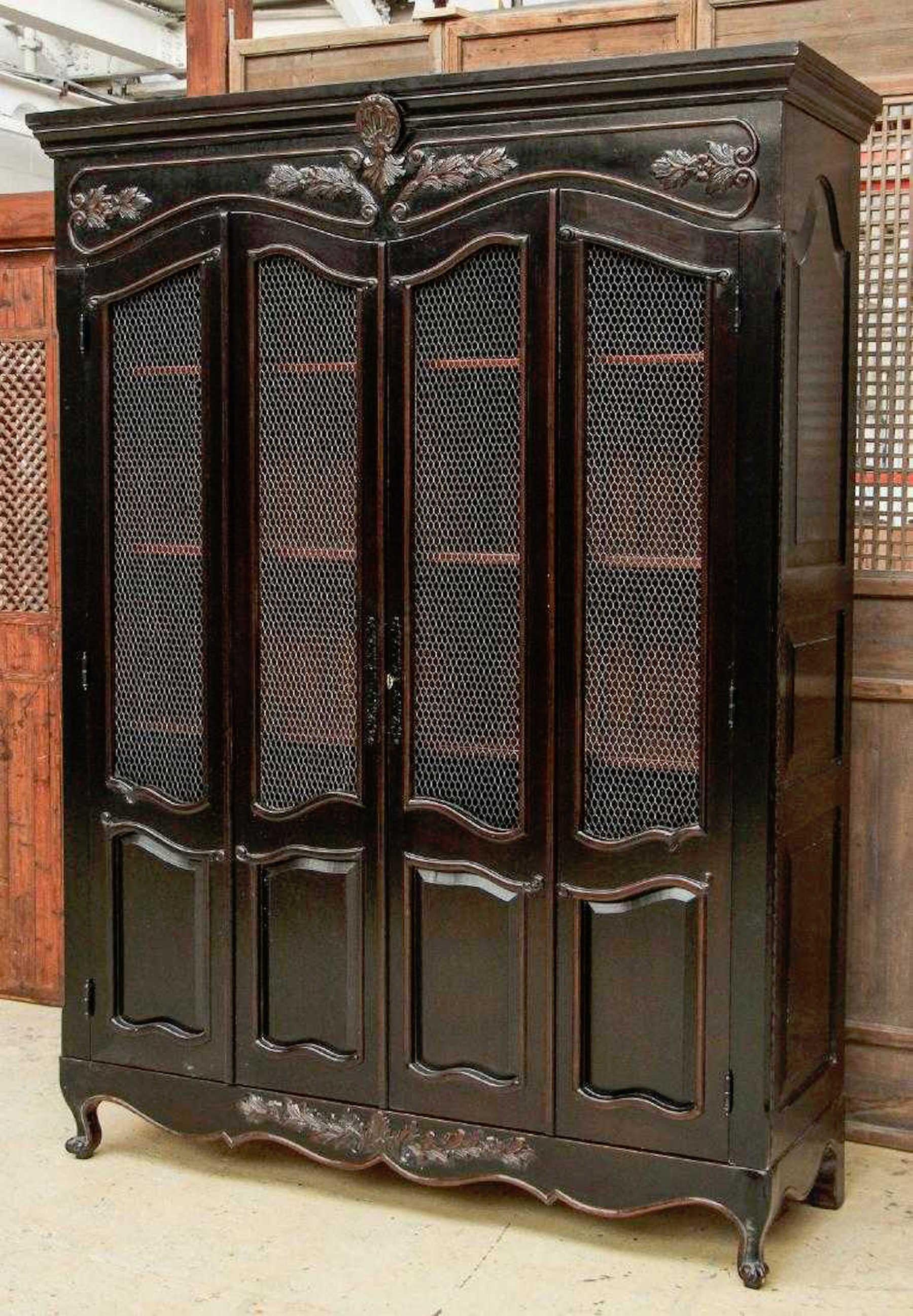 Harcourt display cabinet by Scott Thomas Furniture, part of the Loire Valley collection, in the Chateau Noir Finish. An Exquisite bibliotech with two brass mesh doors, revealing a fitted interior with shelves, two cabinets, and three center drawers,