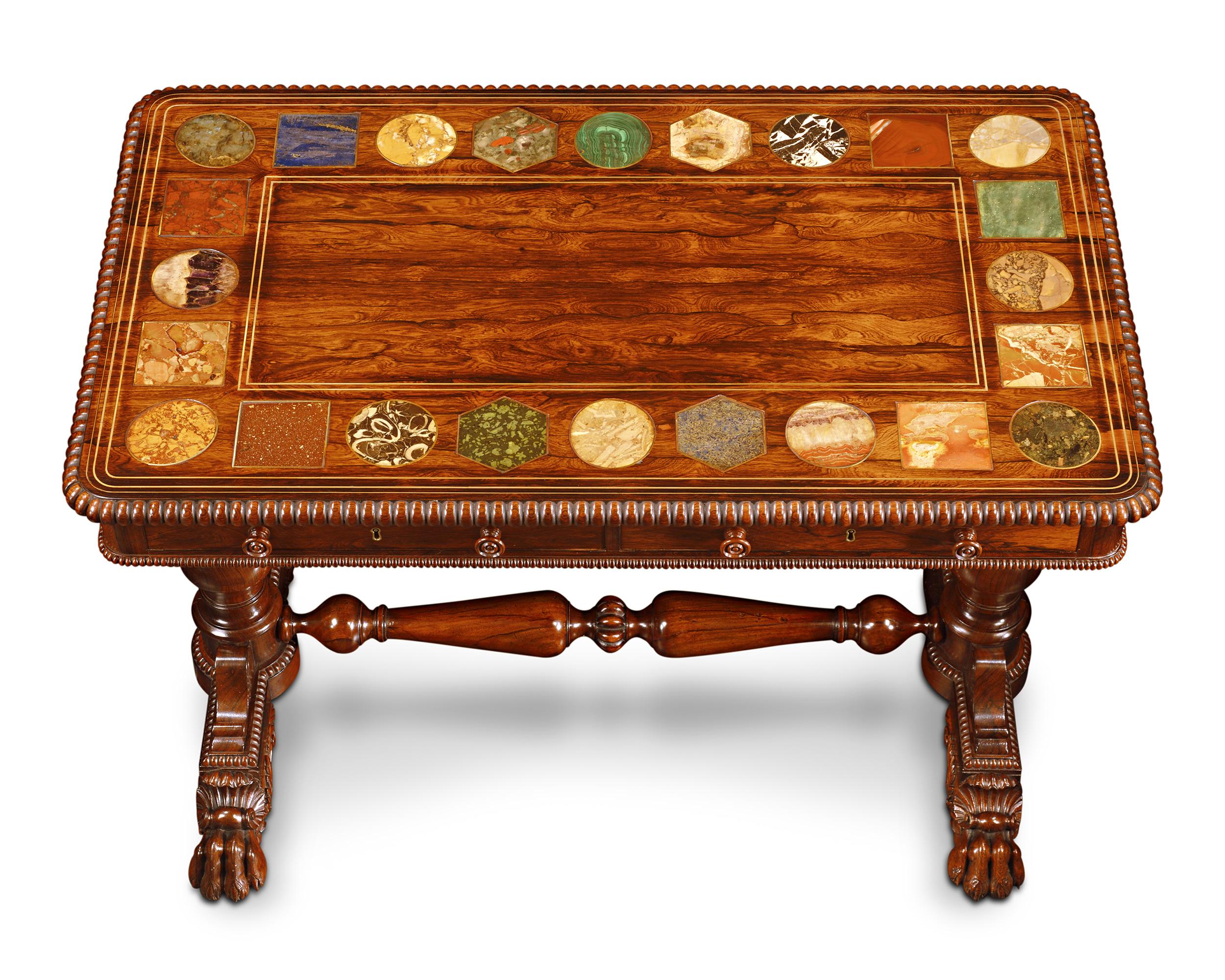 Cette remarquable table centrale en bois de rose, attribuée à la légendaire firme Gillows, met en valeur un artisanat de qualité et des spécimens de pierre dure d'une rareté étonnante. La base de la table est ornementée, avec des pieds en forme de