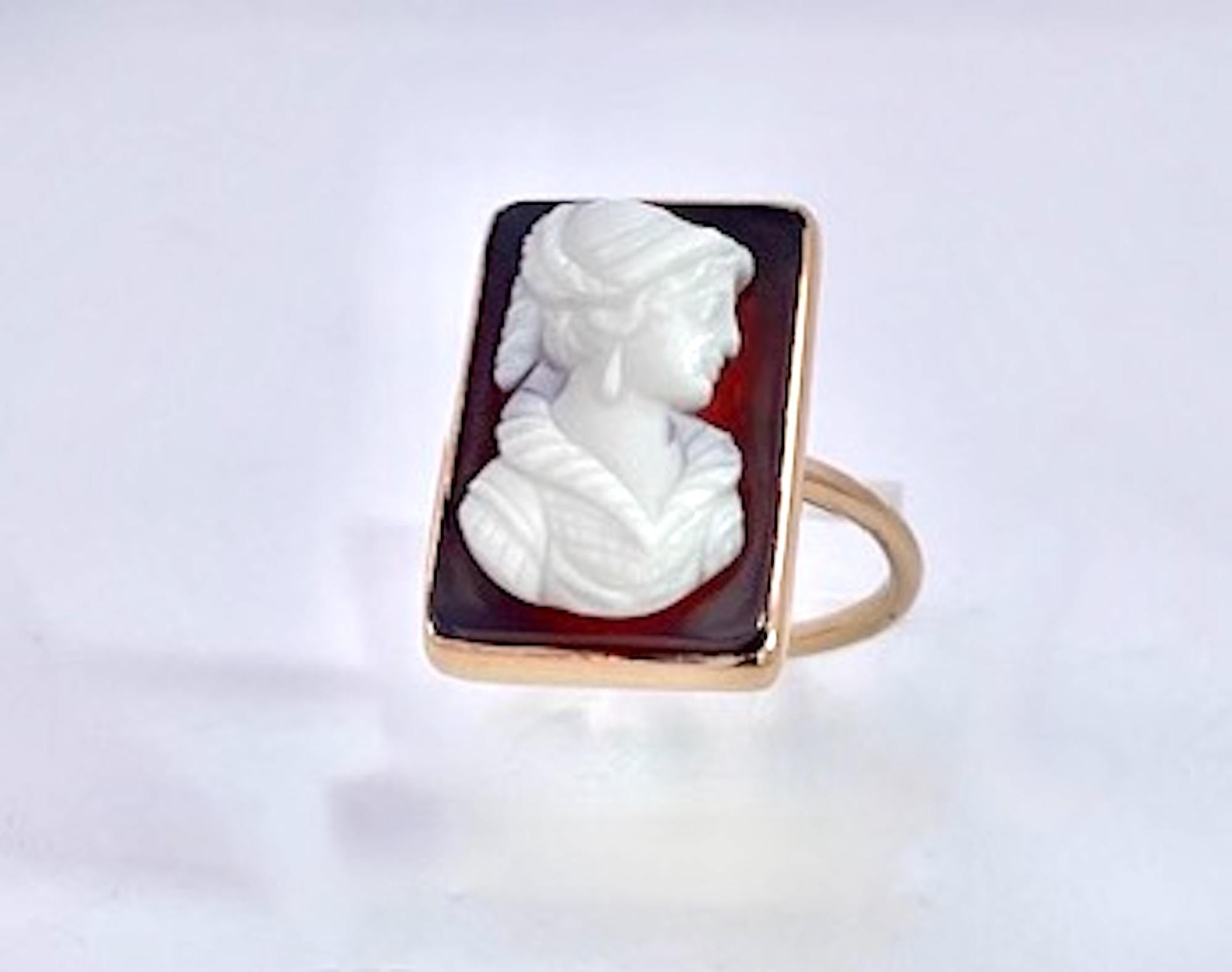 Cette bague camée en pierre dure est réalisée en or jaune 14K.  Il s'agit d'une agate noire avec une femme en relief portant des vêtements médiévaux.  costume.  Cette bague est un rectangle plutôt qu'un format rond ou ovale et pèse 4,64 grammes.  Il