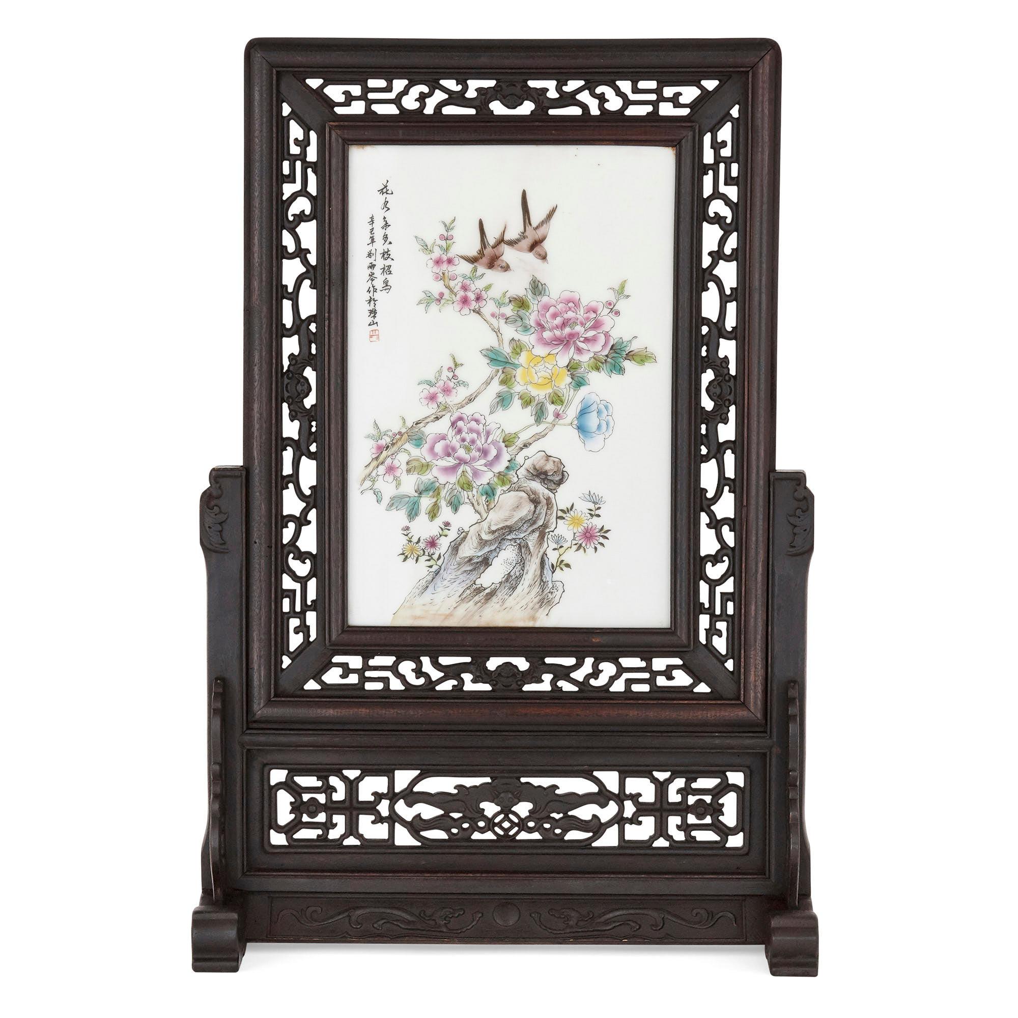 This exquisite Chinese screen is crafted from Hongmu, a dark rosewood from South East Asia. The ornately carved and pierced frame depicts dragons and scrolling foliate shapes. The central porcelain plaque portrays Chinese style birds and flowers in