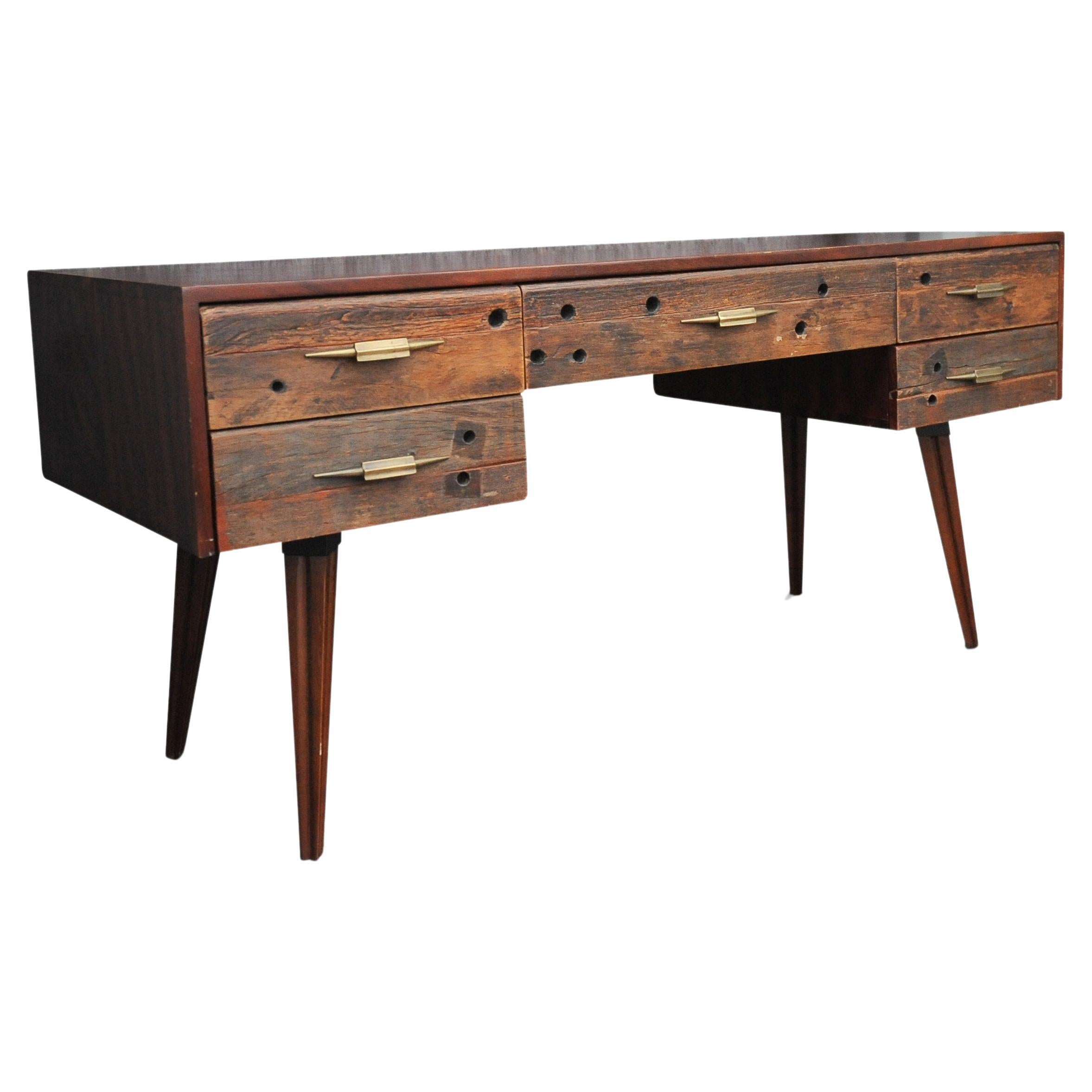 An Impressive Hardwood & Reclaimed Timber Desk Befit With Five Drawers & Gilded Handles.
The external frame tips it's hat to midcentury, the drawer handles reflect and a more art deco styling.

Will work great in a commercial or home