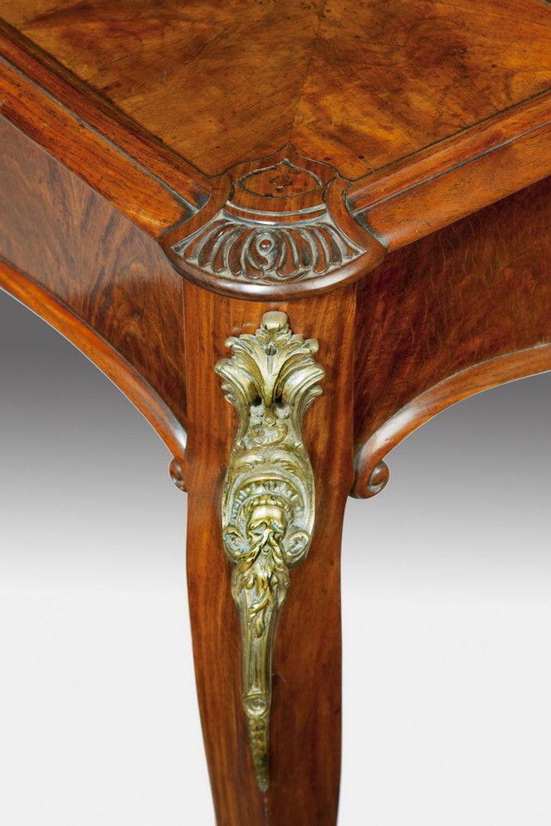 An unusual desk made from oriental timber to an English design.
The shaped top has the typical arrangement of small drawers on three sides, including a pen tray, surmounted by a brass gallery with an openwork Chinese fretwork design. All set upon