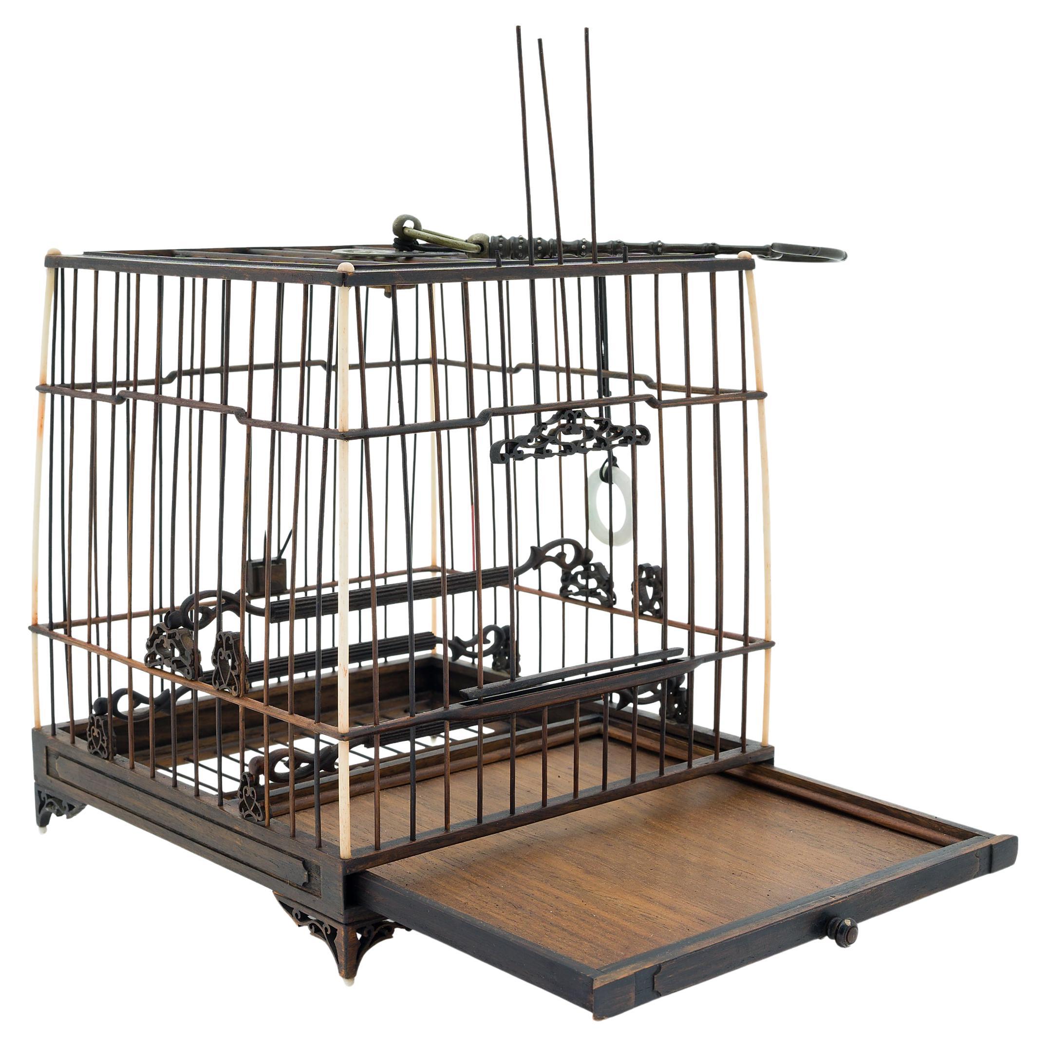 This ornate wooden birdcage was once home to the pet of a Qing-dynasty aristocrat. Dated to the mid-19th century, the cage is carefully assembled of thin wooden rods set within a square frame of bone and carved hardwood. Three wooden perches run the