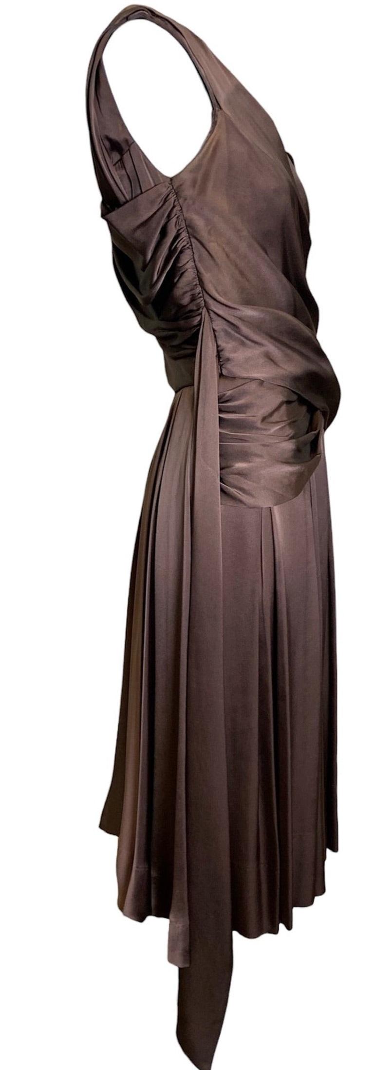 Hardy Amies 1950s Brown silk dress is the perfect choice for a cocktail or party event. Crafted by the esteemed British designer—who has had the honor of dressing the royals—this dress features a dramatic 1950s silhouette and luxurious chocolate