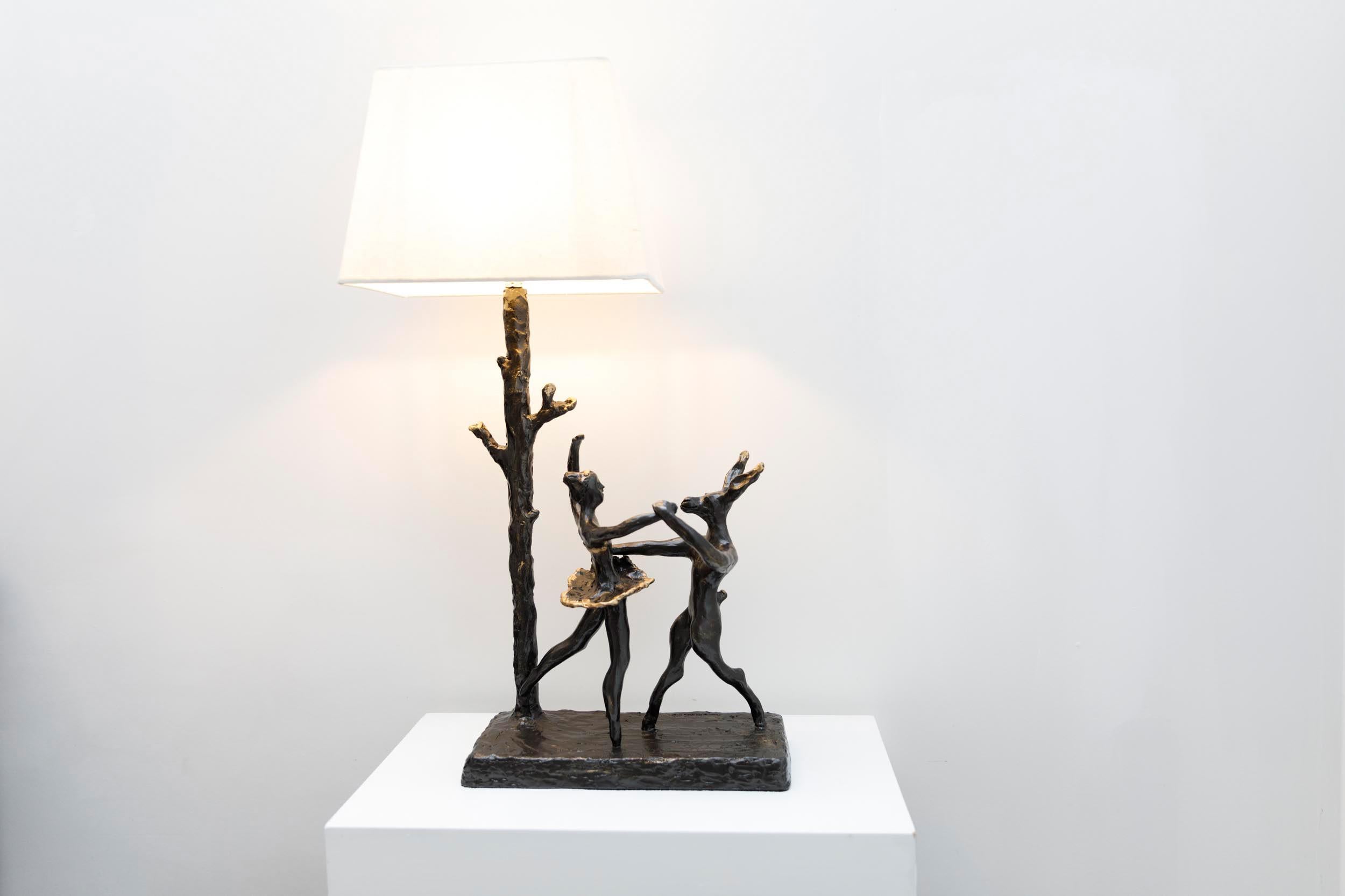 Hare & Ballerina sculptural table lamp, hand crafted, moulded and cast in a mix of resin and bronze. A whimsical lamp of a hare dancing alongside a ballerina by the tree trunk. A charming piece of functional art work creating luminous corner and