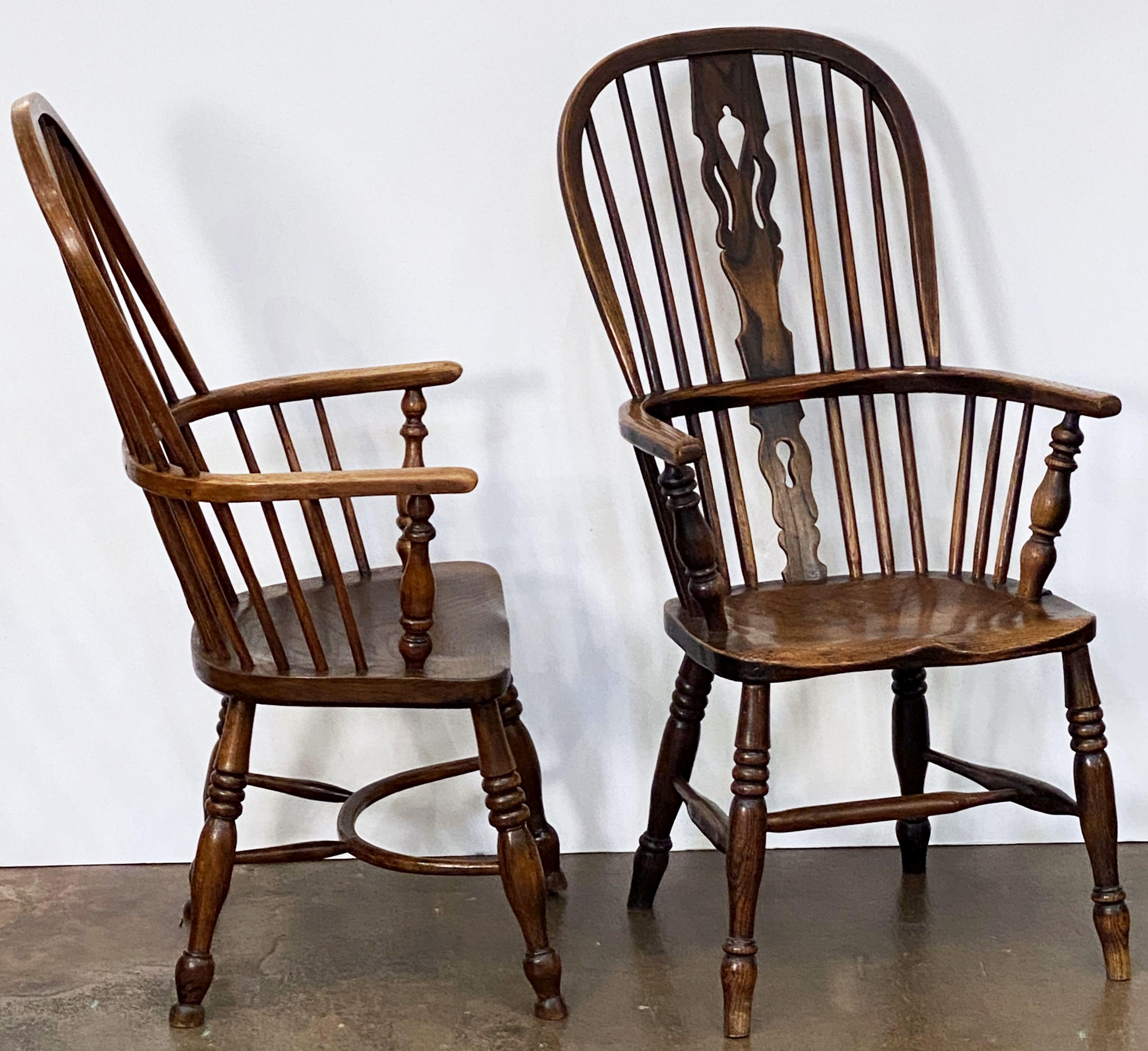 A harlequin set of eight handsome large English Windsor high back chairs, of elm, ash, and oak woods from the early 19th century - each chair featuring bowed top rails and pierced splats and spindle backs, with solid, comfortable seats on either