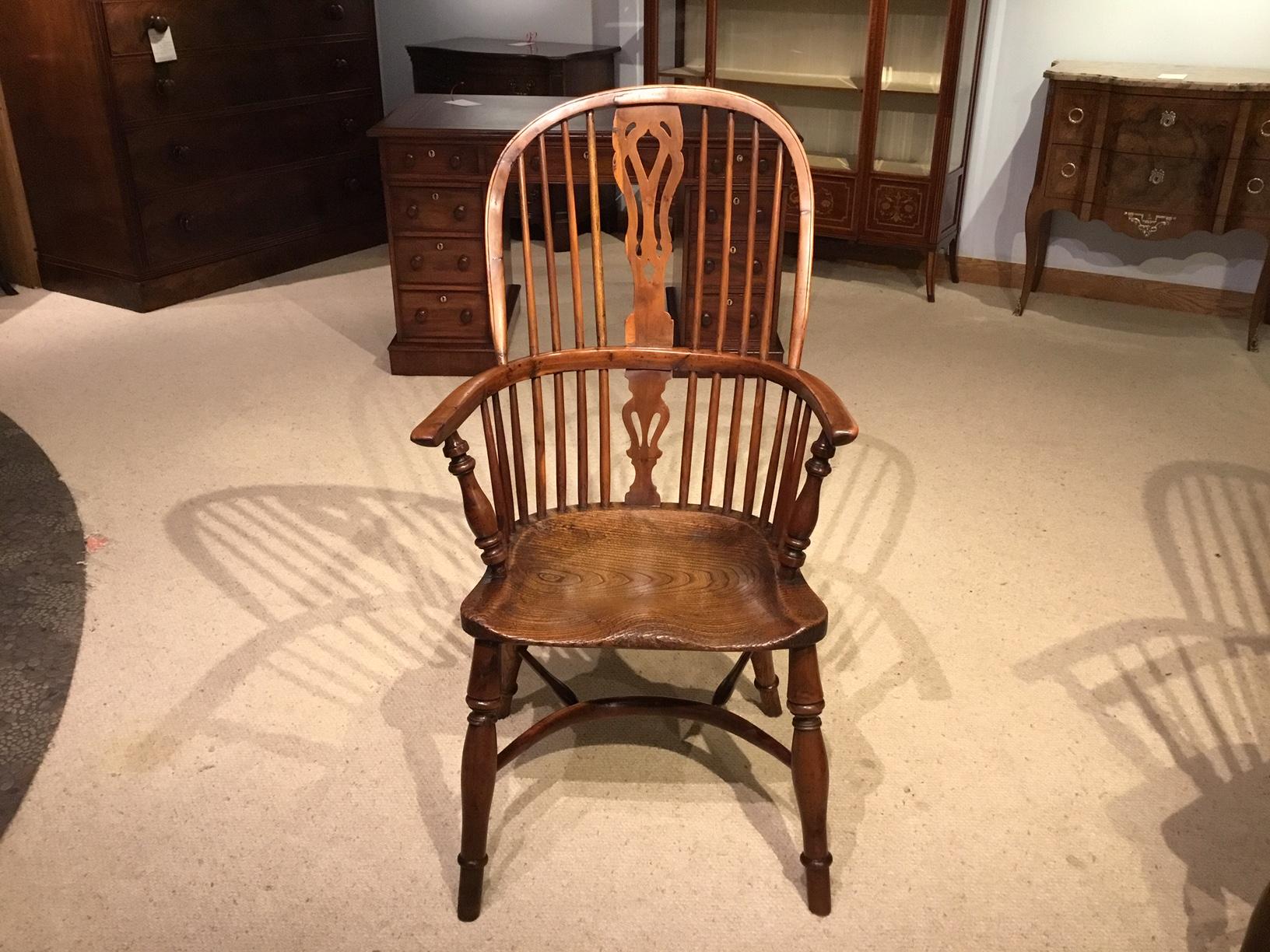 A harlequin set of four yew wood high back Windsor armchairs. Each having a hooped back with pierced horse shaped splat, curved arms and spindle supports, all in yew wood. With ash dished seats and supported on turned yew wood supports with