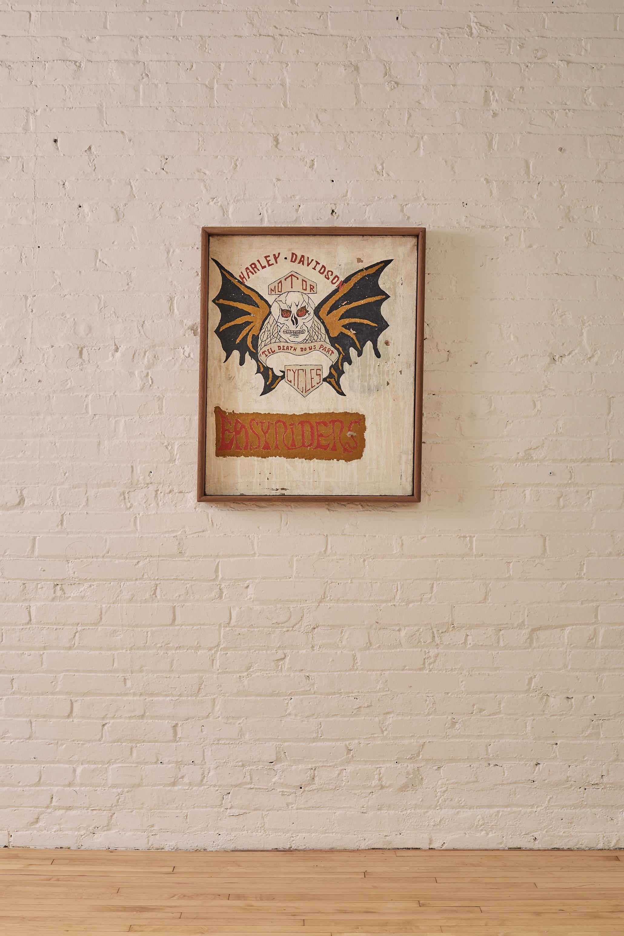 Harley Davidson, Easy Rider Painting encased within a crafted wooden frame. The focal point of the painting is an alternative take on the iconic skull and bat wing Harley-Davidson, Easyrider emblem. The juxtaposition of the biker culture and the