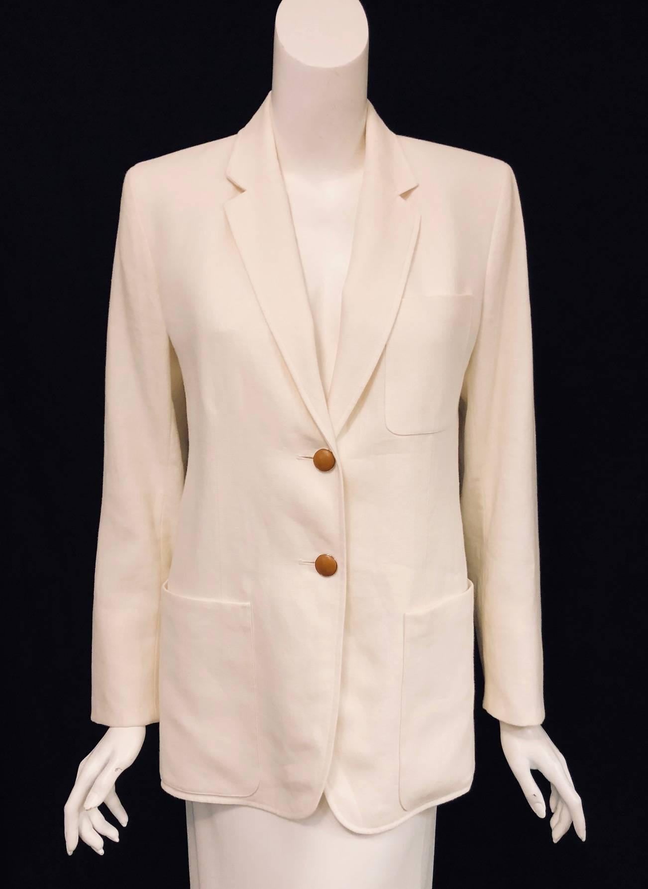 This elegant Hermes jacket is crisp, light and airy.  Features soft ivory linen with two tan leather covered buttons at front of jacket.  Cuffs are fished with four of these same leather covered buttons.  Notch collar and 2 patch pockets completes