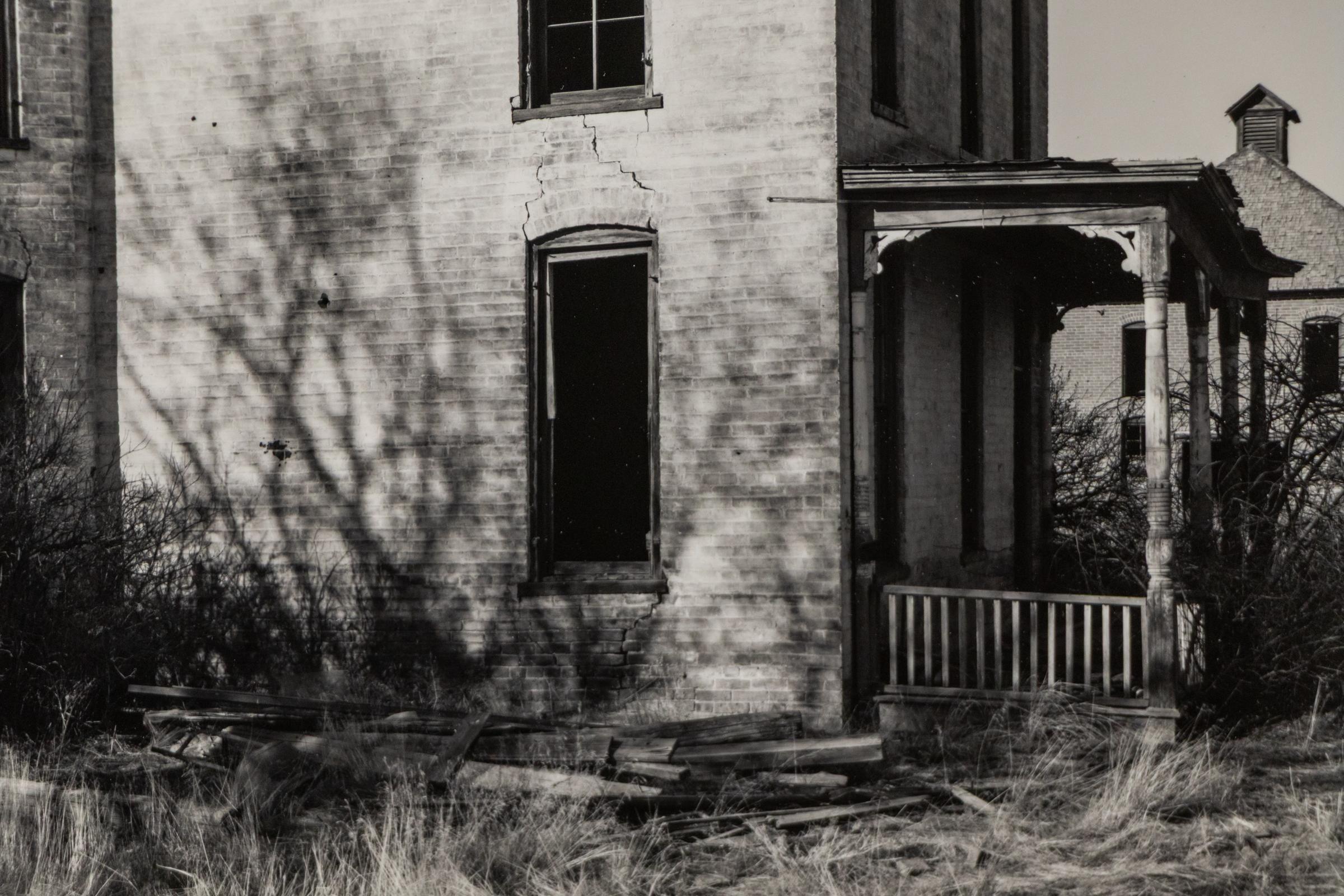 Stimmungsvolle Schwarz-Weiß-Fotografie des amerikanischen Fotografen Harold E. Malde (1923-2007) aus dem 20. Jahrhundert, die ein verlassenes Haus im viktorianischen Stil zeigt, das von einer wilden, überwucherten Vegetation umhüllt ist. Der starke