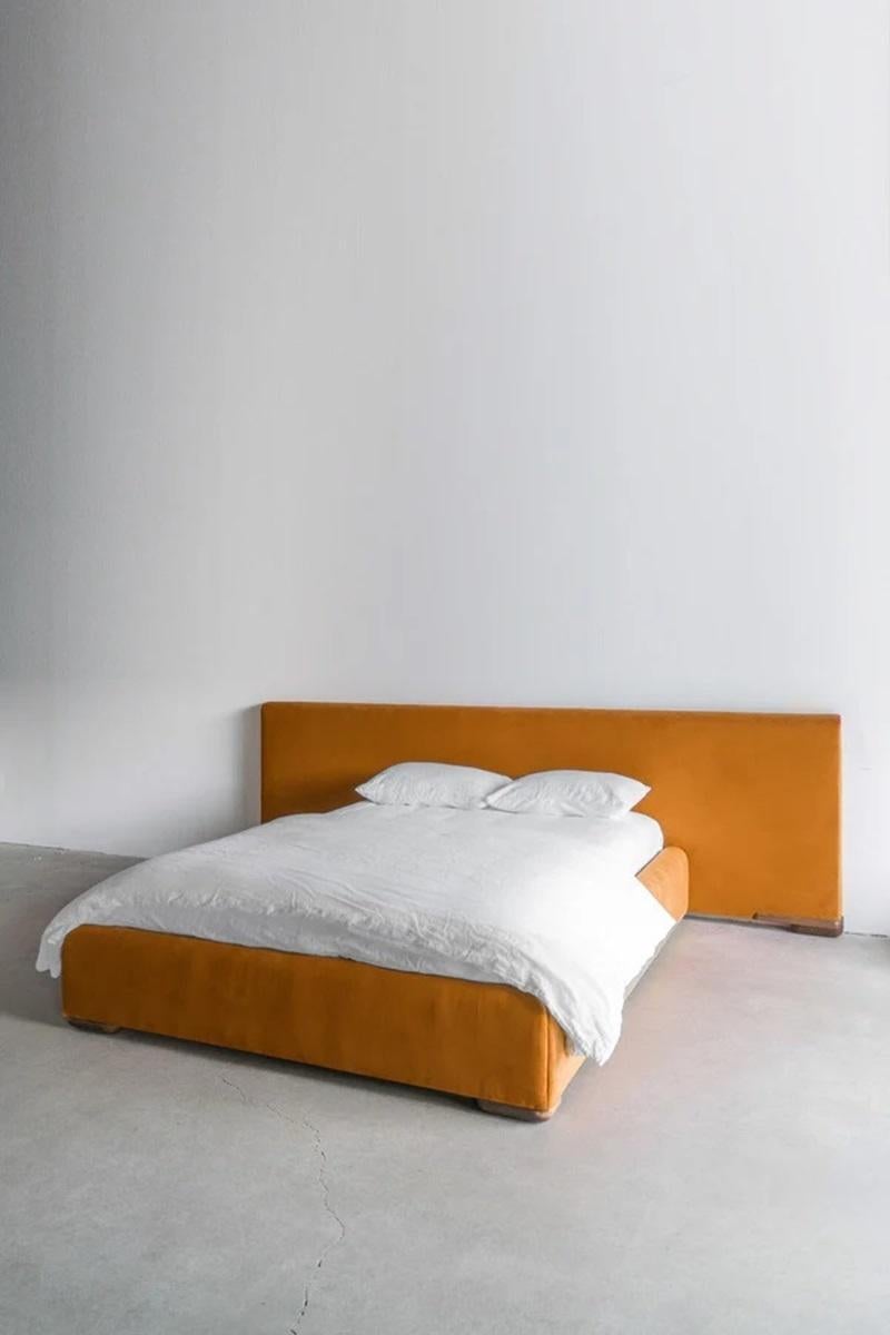 Le lit Harper est conçu en fonction de l'échelle. La tête de lit surdimensionnée constitue une toile de fond minimaliste pour les tables de nuit, les oreillers et la literie. Le lit est entièrement recouvert d'un velours doux aux tons dorés, avec