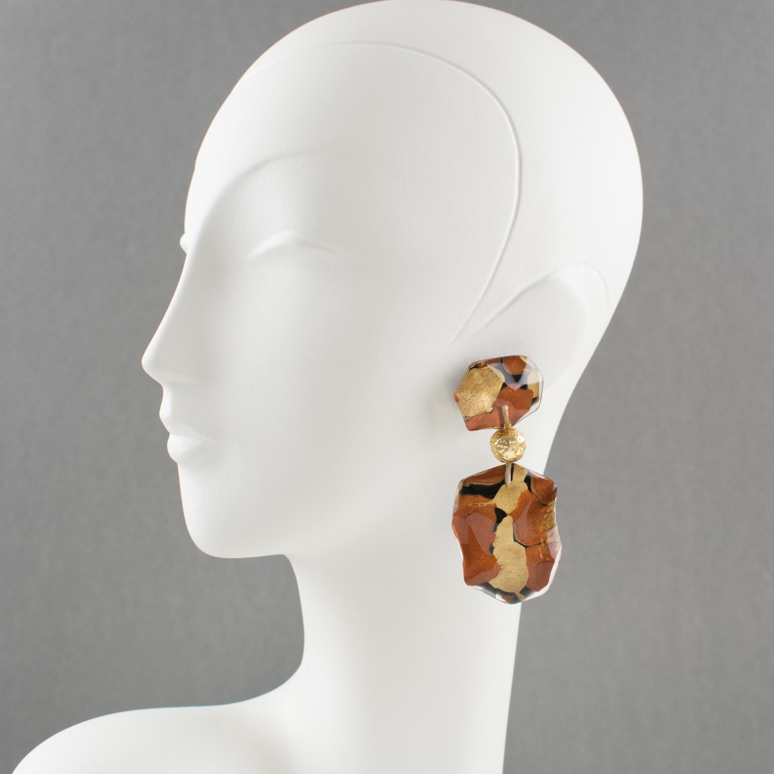 Exquisite oversized Lucite clip-on earrings designed by Harriet Bauknight for Kaso. Dangling shape with an asymmetric design featuring dimensional domed lucite elements with beveling. Clear Lucite with bronze and copper color inclusions with