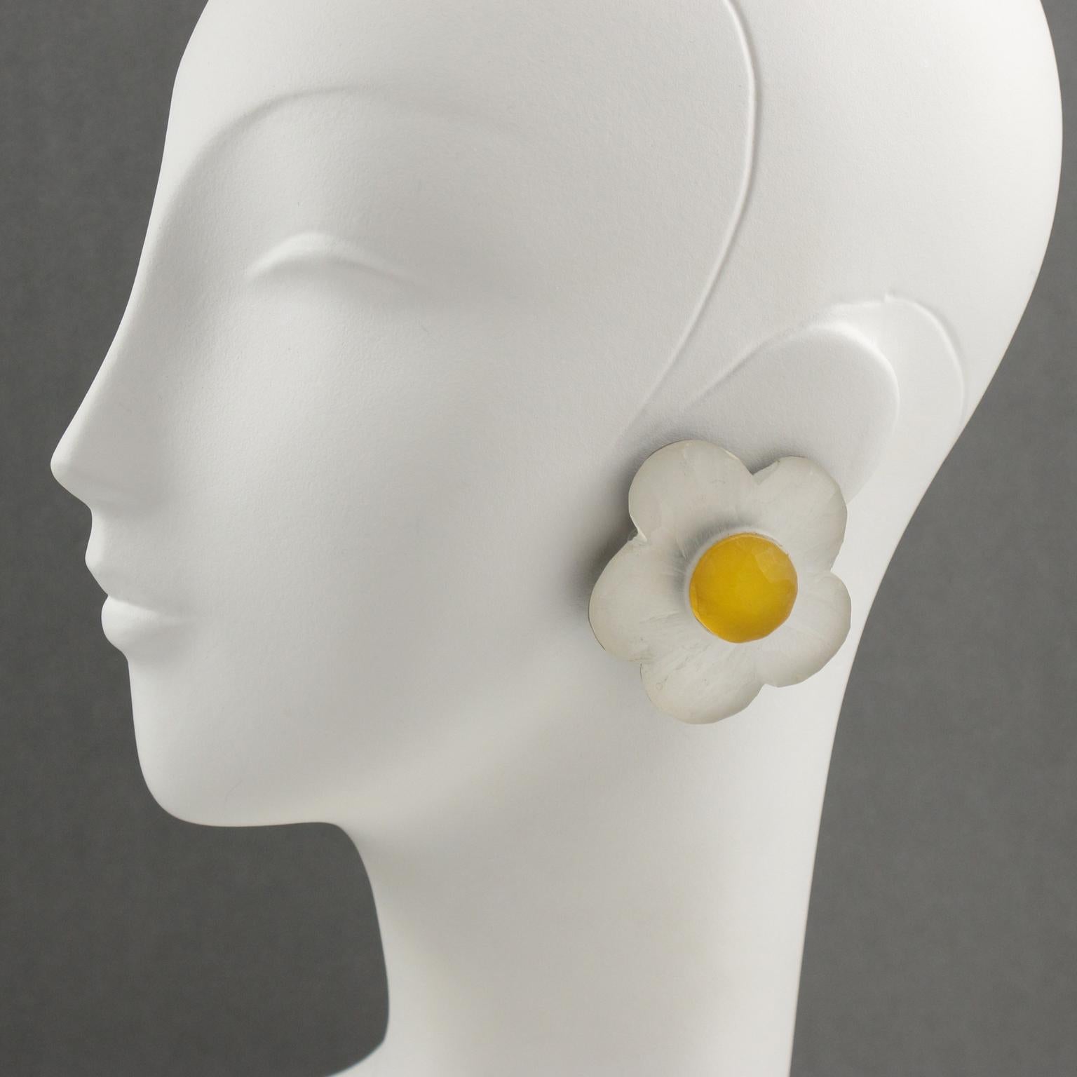 Harriet Bauknight for Kaso designed those gorgeous white and yellow frosted lucite or resin clip-on earrings. They boast a dimensional shape, all carved and textured, featuring a daisy flower in frosted white and yellow colors. One earring still has