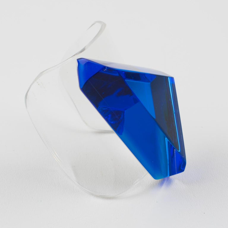 Striking Lucite cuff bracelet designed by Harriet Bauknight for Kaso. Clear lucite oversized rigid cuff shape topped with large geometric ornament. Amazing Lucite ornament featuring geometric faceted large triangle in intense blue lagoon color. Kaso