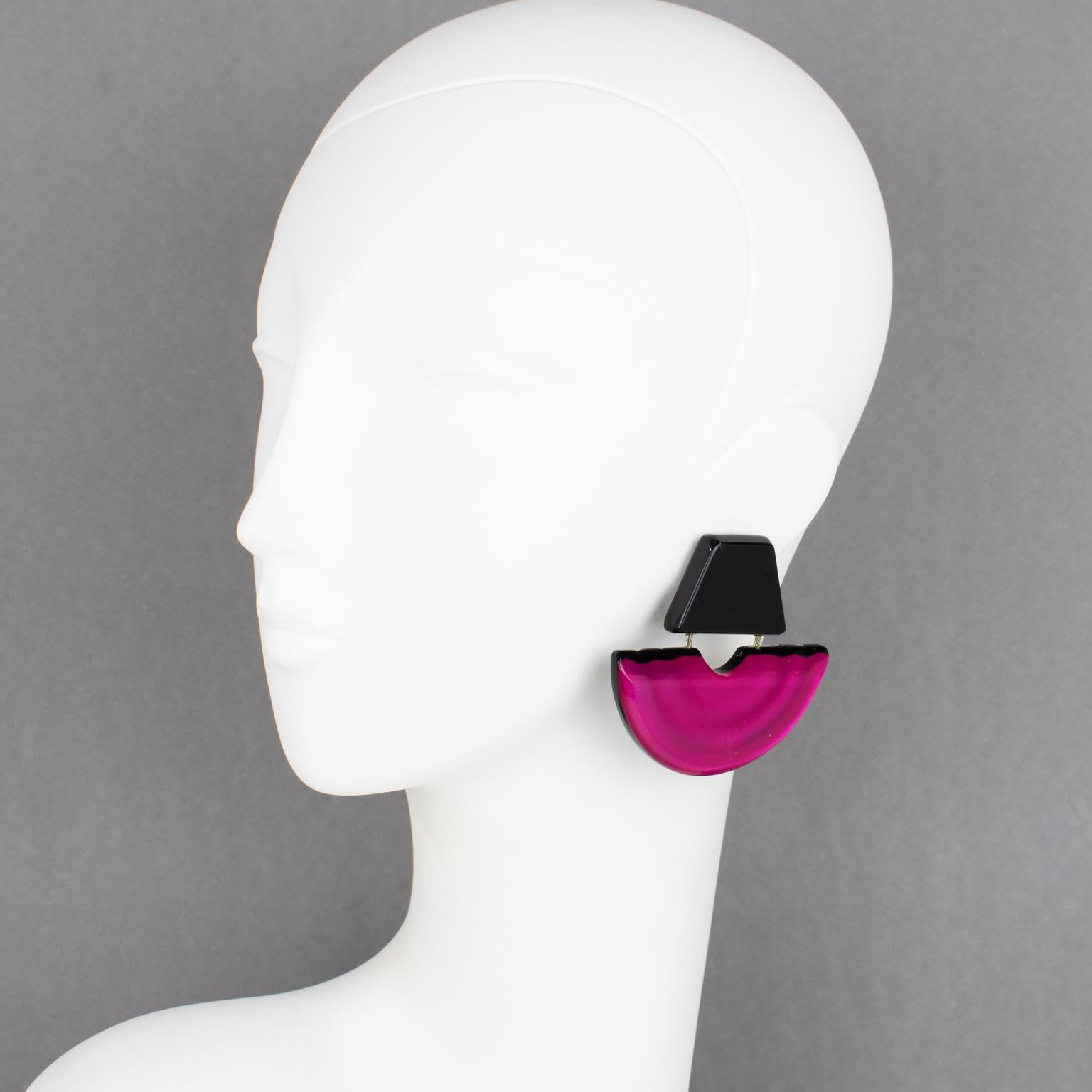 Harriet Bauknight for Kaso designed these sculptural Lucite clip-on earrings. The geometric dangling shape features a giant fan with pearlized inclusions and large beveling. The elements are linked together with silver-tone metal chains. The
