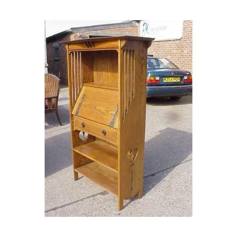 Libreria a bureau in stile Glasgow di Harris Lebus, modello 156, con zona espositiva nella parte superiore, cornice sottilmente sagomata con 3 supporti sagomati al centro e libreria sottostante con fianchi a doghe. Un'area di scrittura aperta con