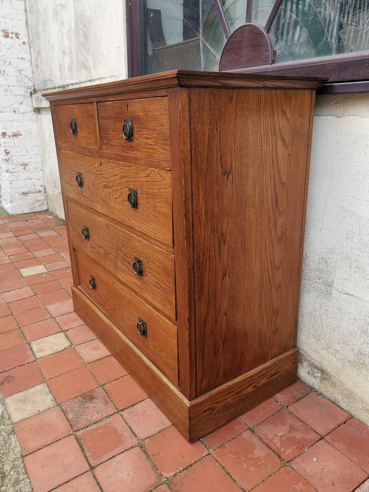 Harris Lebus. Tottenham. London. 
An English Arts and Crafts oak chest of two over three drawers with brass and steel ring pull handles, and stamped registered design numbers to the drawers and H. L. L. stamped to the locks.