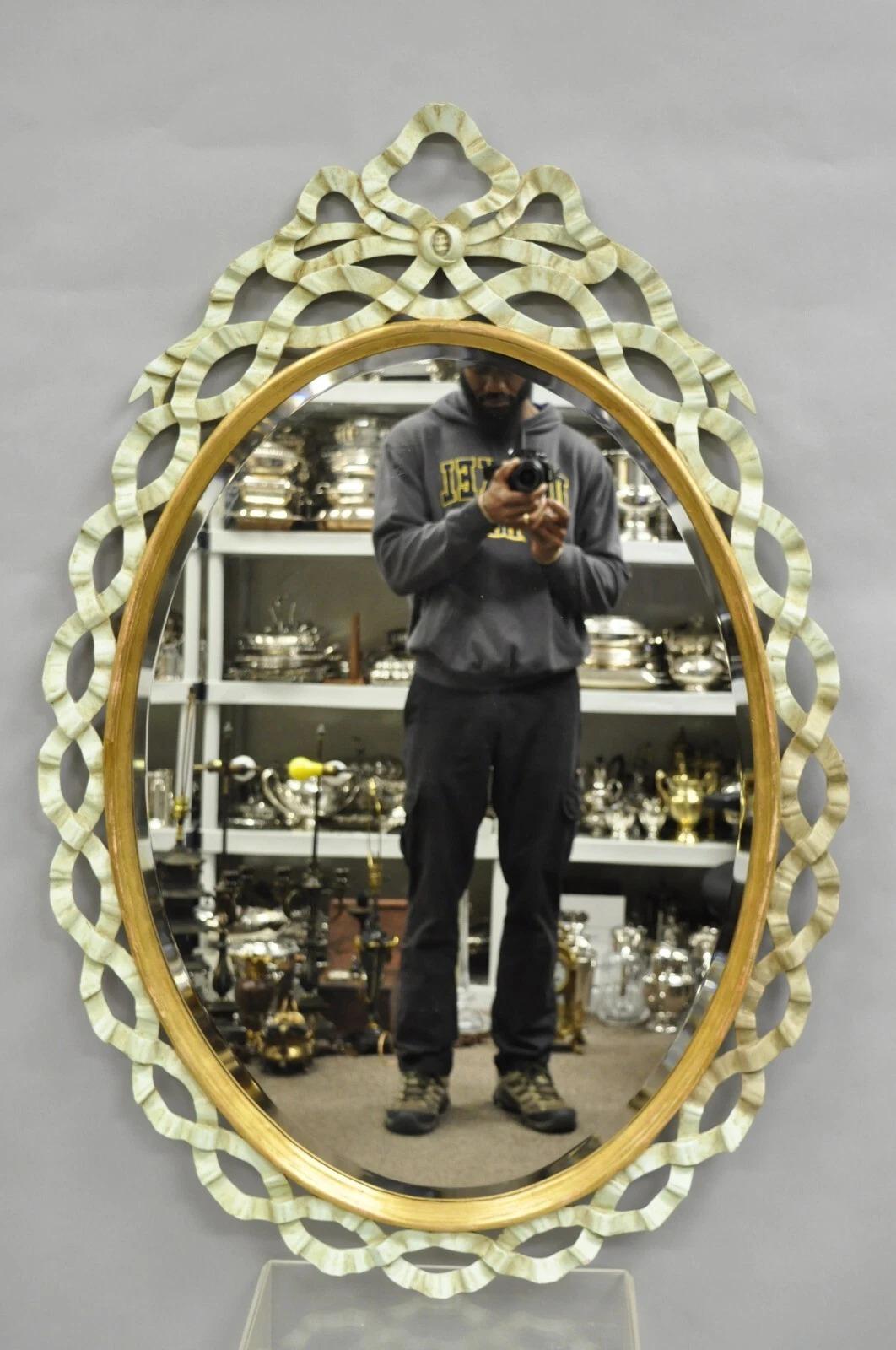 Vintage Harrison & Gil Light Blue Painted Italian Hollywood Regency Carved Wood Ribbon Oval Wall Mirrors - a Pair. Item features beveled glass, gold gilt trim, and original label. Circa Mid 20th Century. Measurements: 49