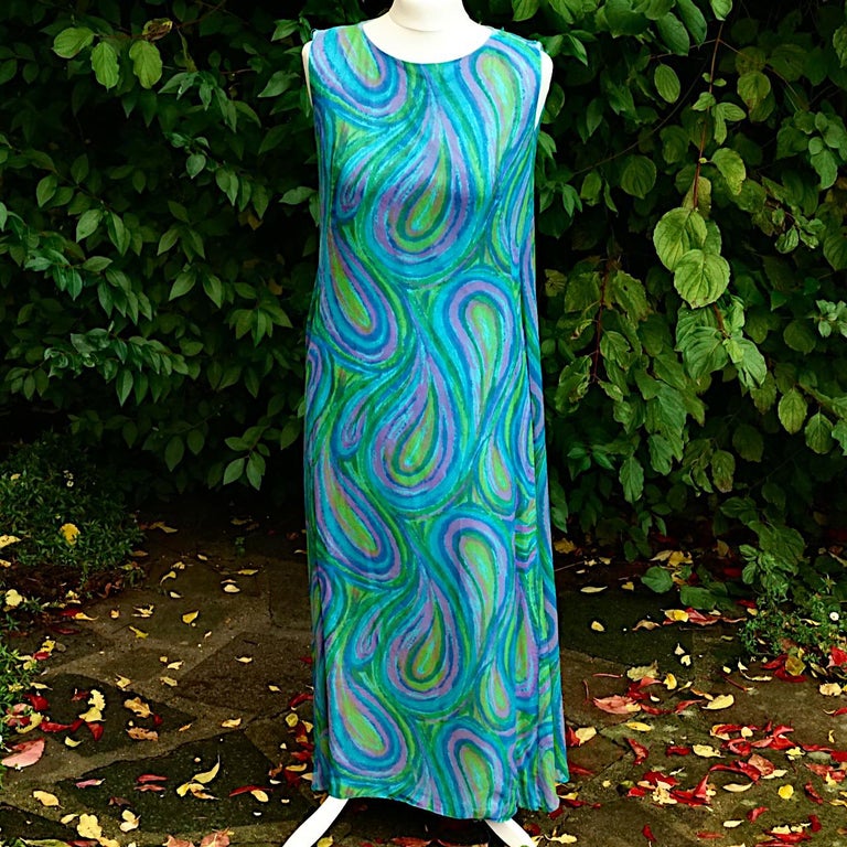 Beautiful Harrods blue green and mauve silk chiffon maxi dress, in a simple paisley pattern. It is fully lined with pale blue silk. There is a zip at the back ending with a bow at the neck, and popper and hook closure some of which will need