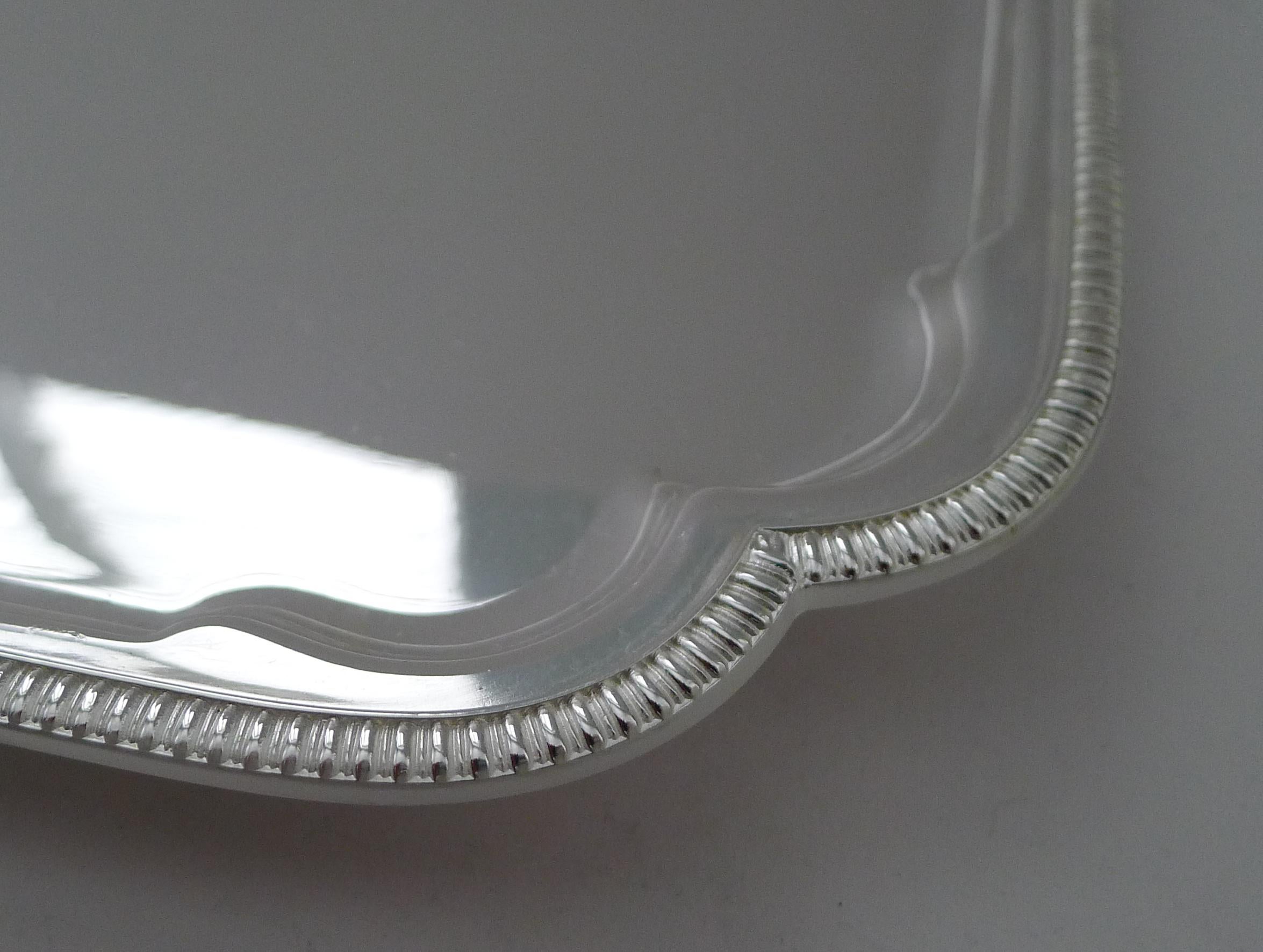 Una bandeja de cóctel muy elegante hecha de plata chapada que acaba de ser limpiada y pulida profesionalmente en nuestro taller de orfebrería, devolviéndole su antiguo esplendor.

De forma rectangular con esquinas perfiladas y un borde en relieve