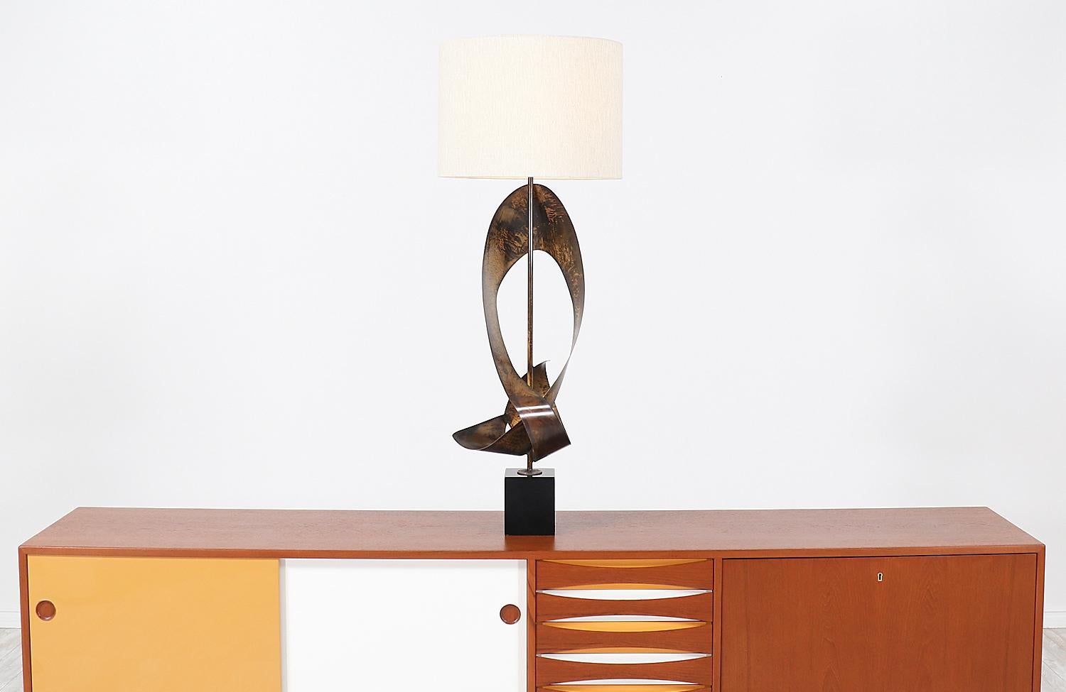 Mid-Century Modern Brutalist ribbon-shaped table lamp designed in the United States by artist Harry Balmer for Laurel Lamp Co., circa 1960s. This dazzling lamp design features an abstract ribbon styled patinated steel body that sits on a black