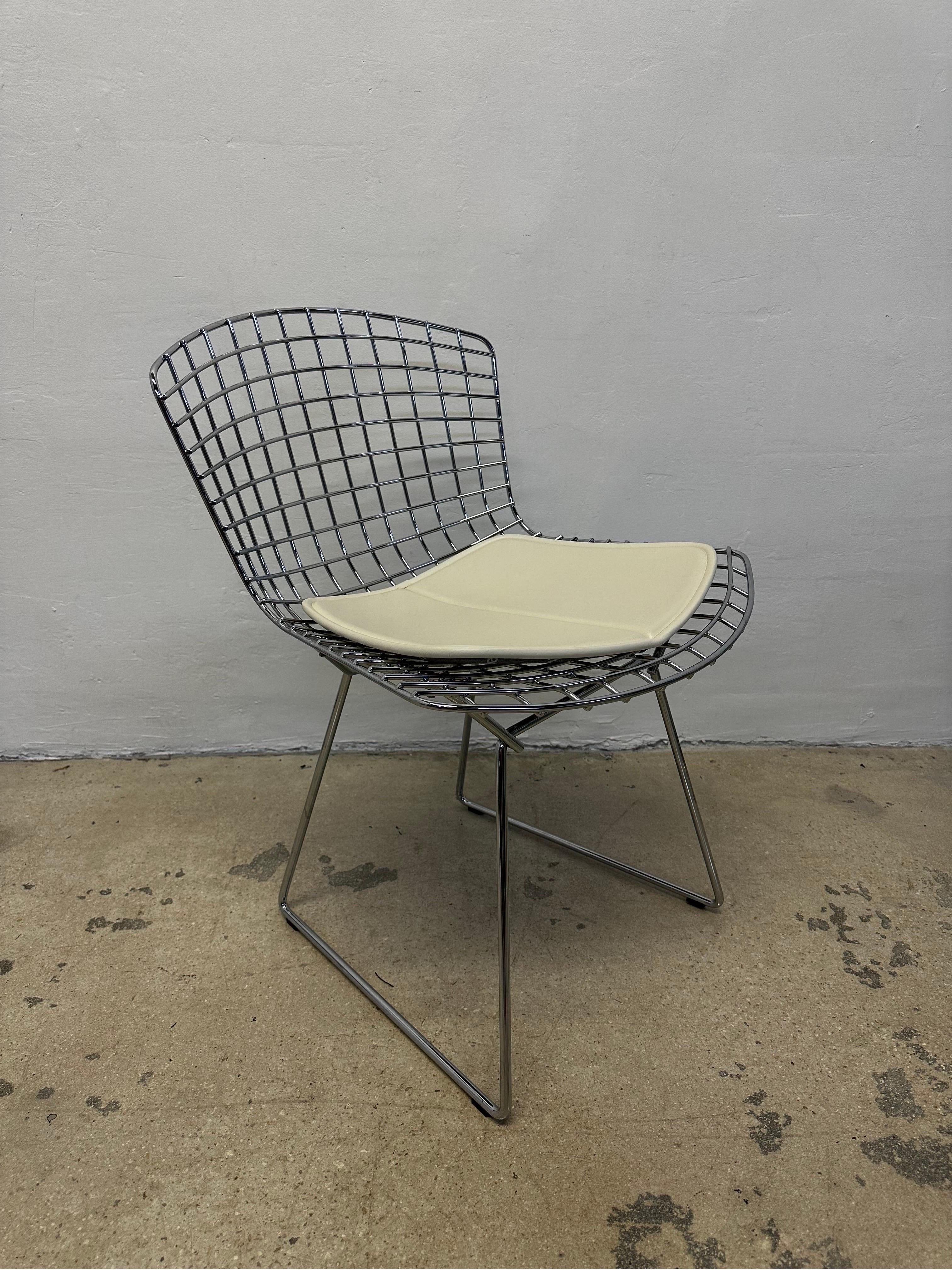 Set of six chrome wire dining chairs with cream colored leather cushions by Harry Bertoia for Knoll.