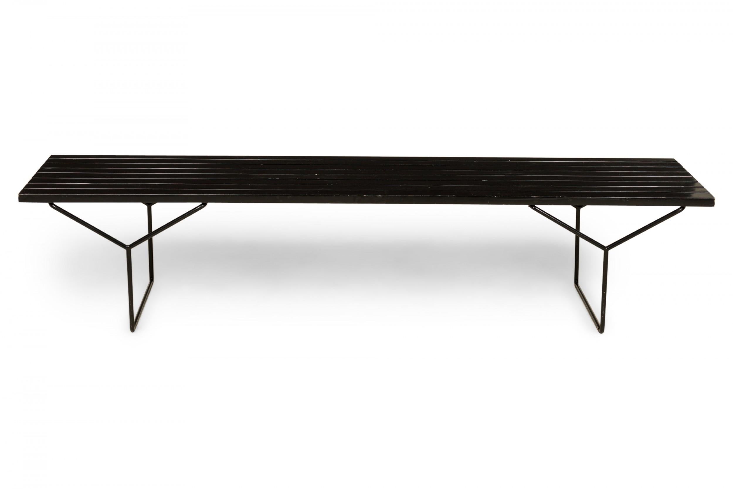 American Mid-Century rectangular bench with a black lacquered slat wood seat resting on two Y-shaped black iron legs. (HARRY BERTOIA FOR KNOLL ASSOCIATES).
 