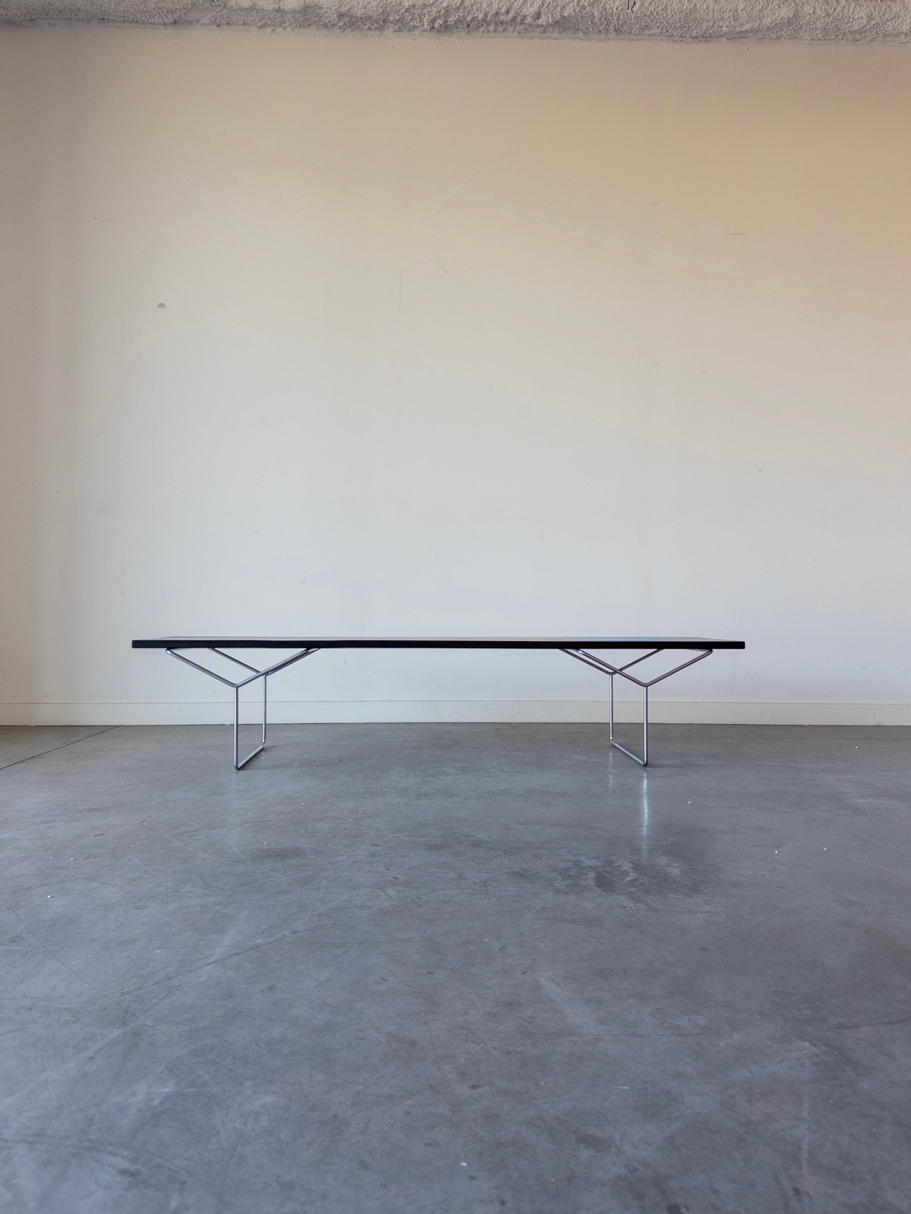 This is an iconic slatted wood bench designed by Harry Bertoia and produced by Knoll, 1980s. The bench was constructed using lacquered wood for the slats, and has a base of chrome-plated steel.