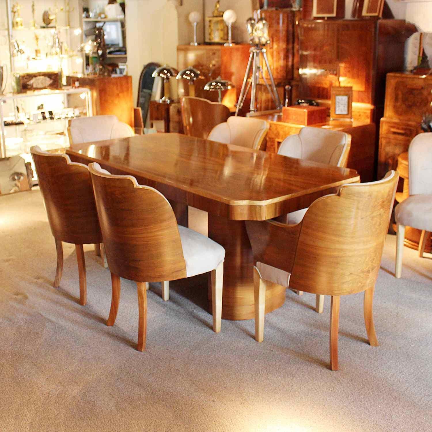 An Art Deco dining table with four chairs and two carvers by Harry & Lou Epstein. Figured walnut table with satinwood banding. Chairs wrapped in walnut with walnut and satinwood legs. Upholstered in oatmeal Alcantara suede