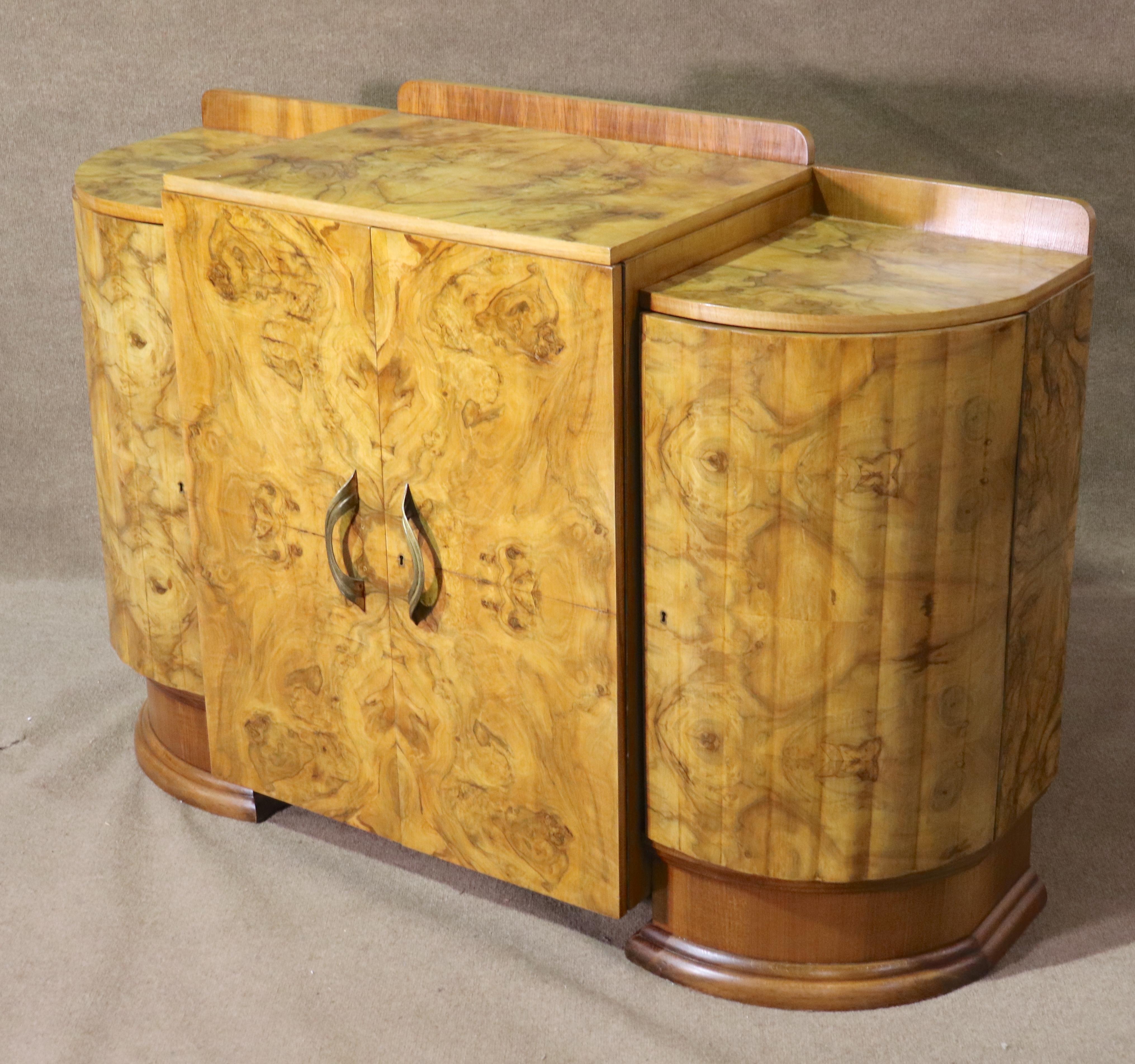 This burl walnut cabinet is designed in an Art Deco style with a floating middle and two flanking columns. Each cabinet space has shelving, the handles are brass, the top is also covered in burl veneer.
Please confirm location NY or NJ