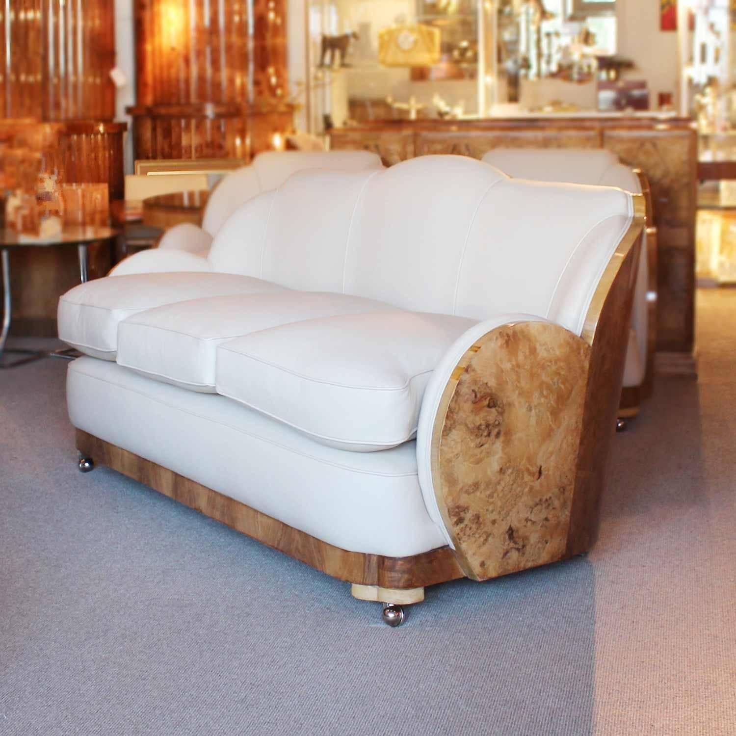 An Art Deco cloud suite by Harry & Lou Epstein. Three-seat cloud back sofa and two armchairs, with contrasting burr and straight grain walnut wraps. Upholstered in cream leather.

Dimensions: Sofa H 89cm, W 172cm, D 95cm, seat H 51cm, seat D 67cm