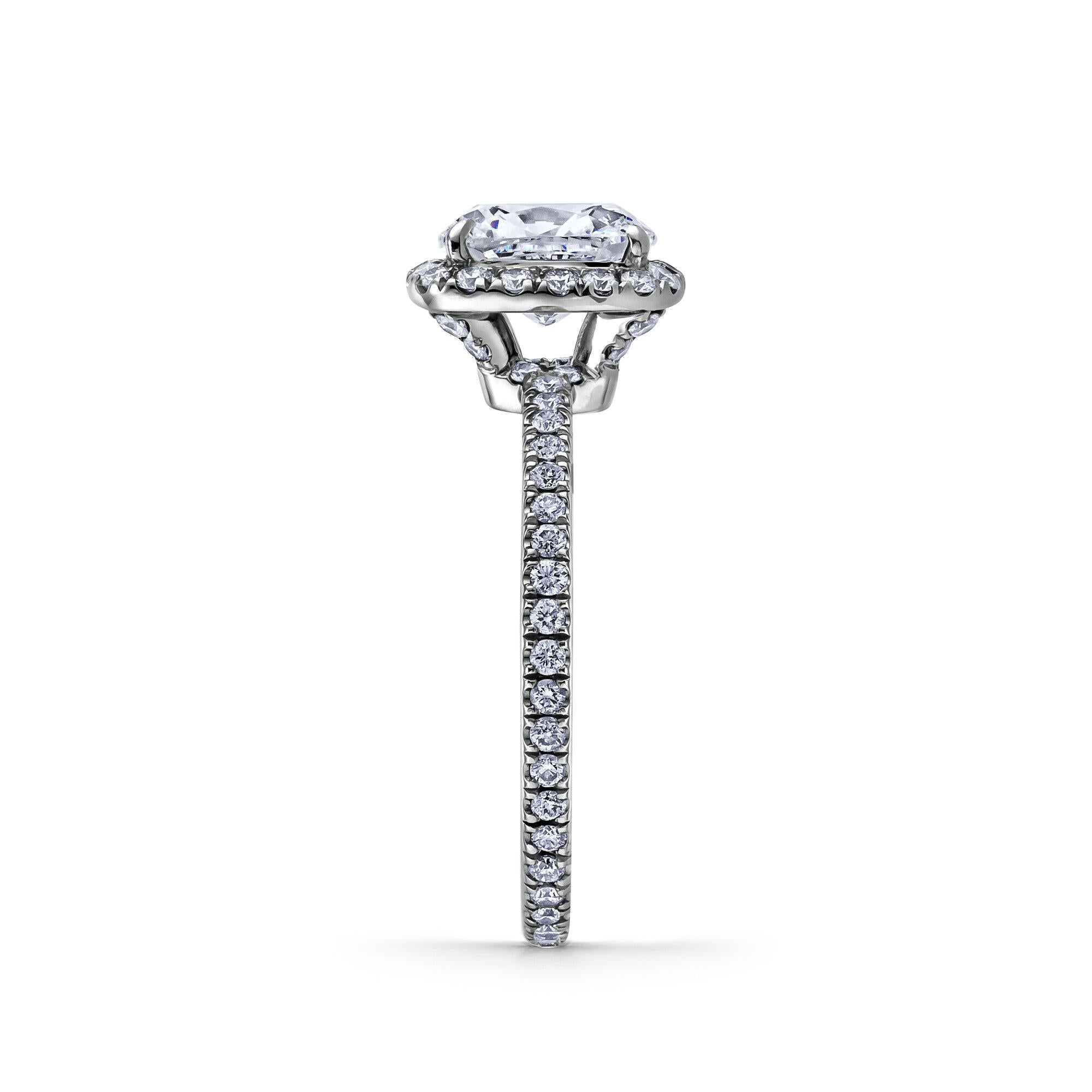 From the House of Harry Winston, this 1.28 carat cushion cut diamond platinum engagement ring symbolizes true love that will last a lifetime. Framed by pave-set round brilliant cut diamonds and a pave-set round brilliant cut diamond band weighing a