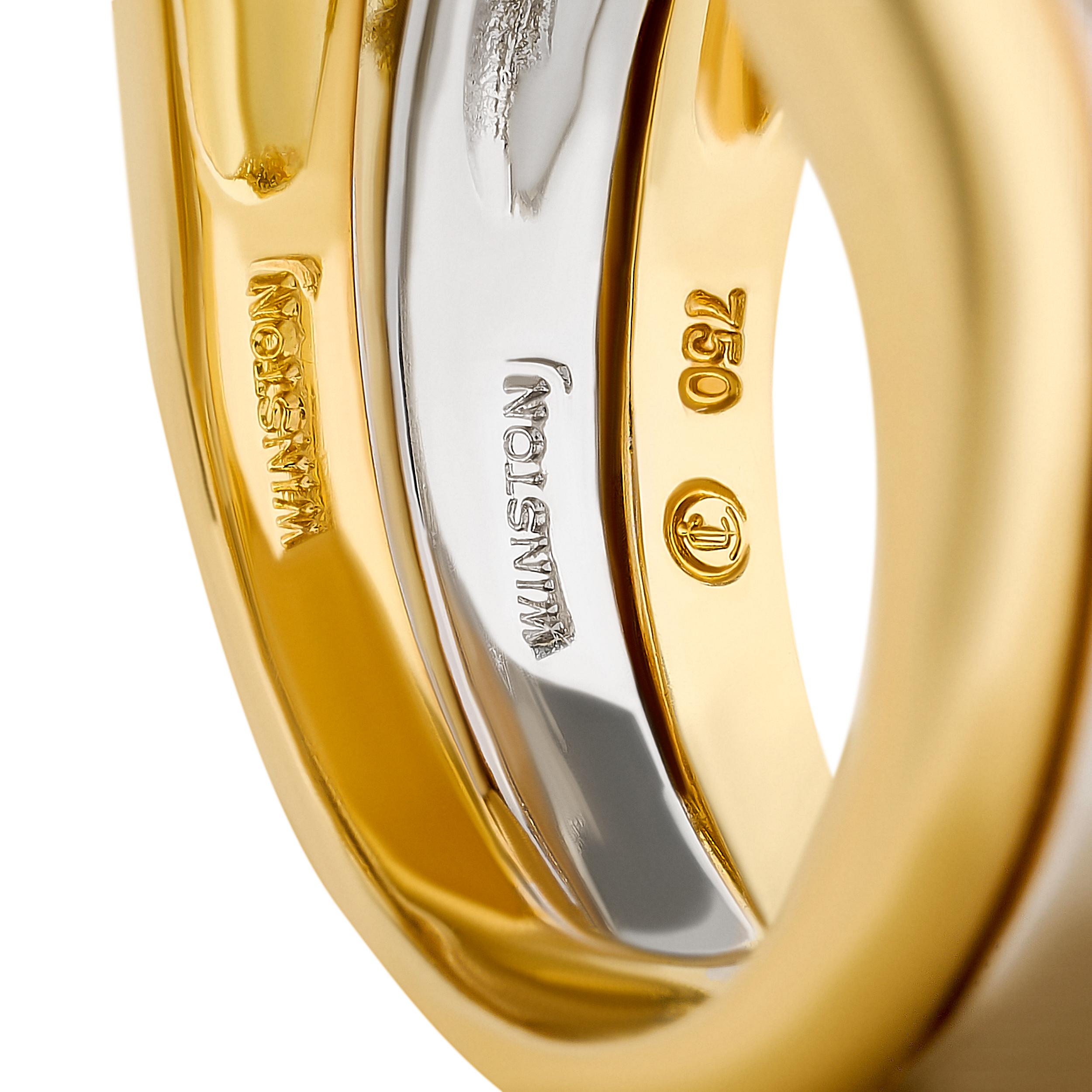 Este opulento anillo Harry Winston presenta un diseño de tres filas, con dos bandas exteriores de diamantes engastados en pavé de oro amarillo de 18k que enmarcan una banda central de platino también engastada con diamantes en pavé, cada fila