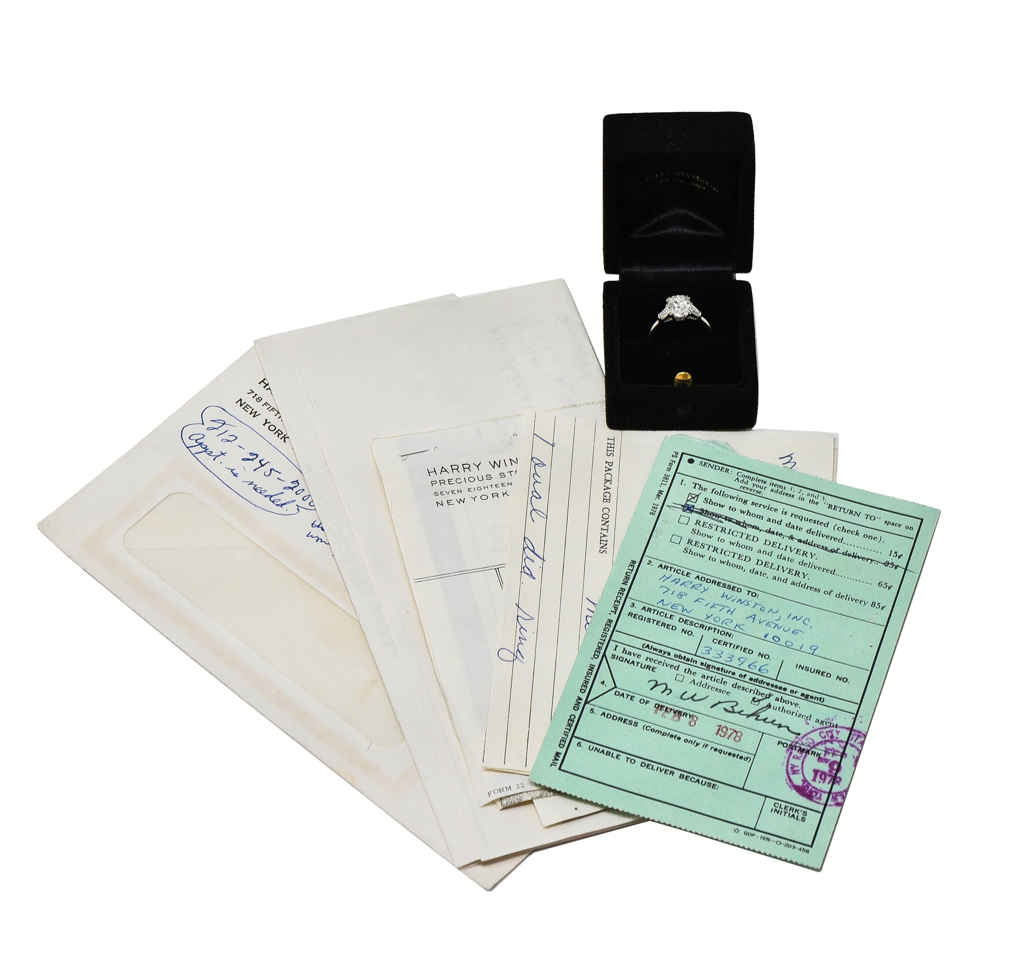 Centering an oval cut diamond weighing 1.99 carats - F color with SI2 clarity
Basket set with split talon prongs - flanked by tapered baguette cut diamonds 
Weighing 0.35 carat total - well matched to center 
Bar set in cathedral shoulders