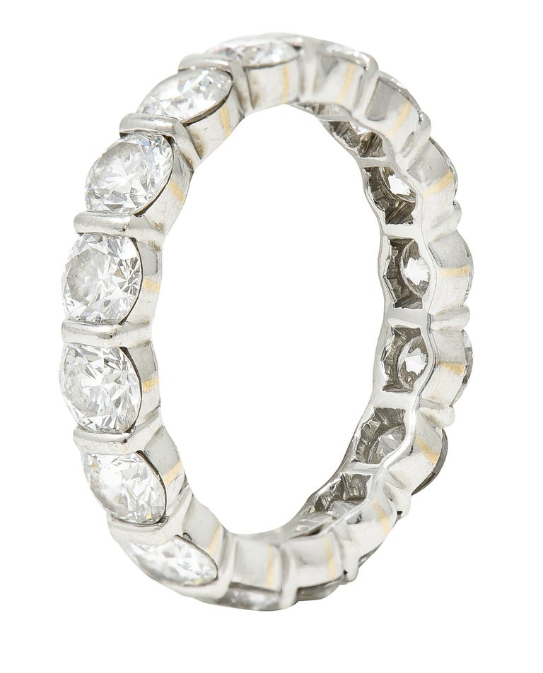 Eternity band ring is bar set fully around by round brilliant cut diamonds. Weighing in total approximately 3.50 carats - F/G color with VS clarity. Stamped PT950 for platinum. Numbered with maker's mark for Harry Winston. Circa 21st century. Ring
