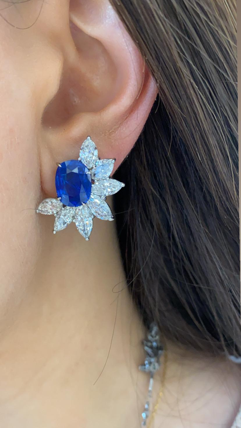 14 White Marquise diamonds totaling in 7.2 carat weight are clustered around magnificent ceylon unheated oval sapphires totaling in 9.98 carats. Set in platinum. In true Harry Winston style, these earring feature a cluster design of brilliant