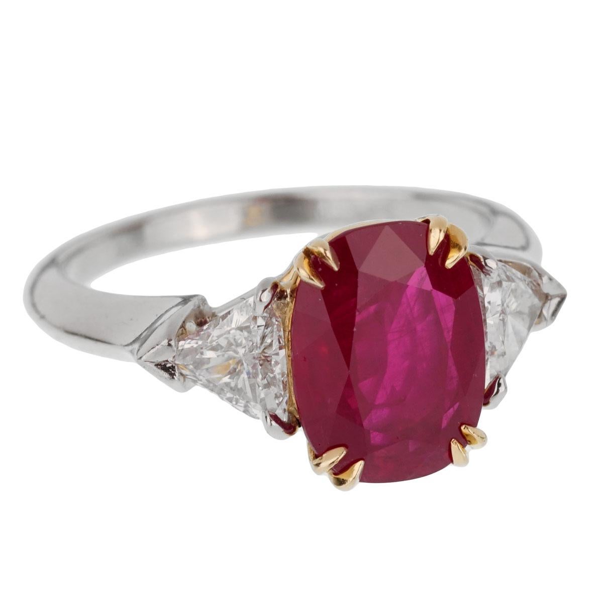 An iconic Harry Winston ring showcasing a 3.02ct Burma ruby set in 18k yellow gold flanked by 2 trillion cut diamonds in platinum. The ring measures a size 5 1/2 and can be resized.