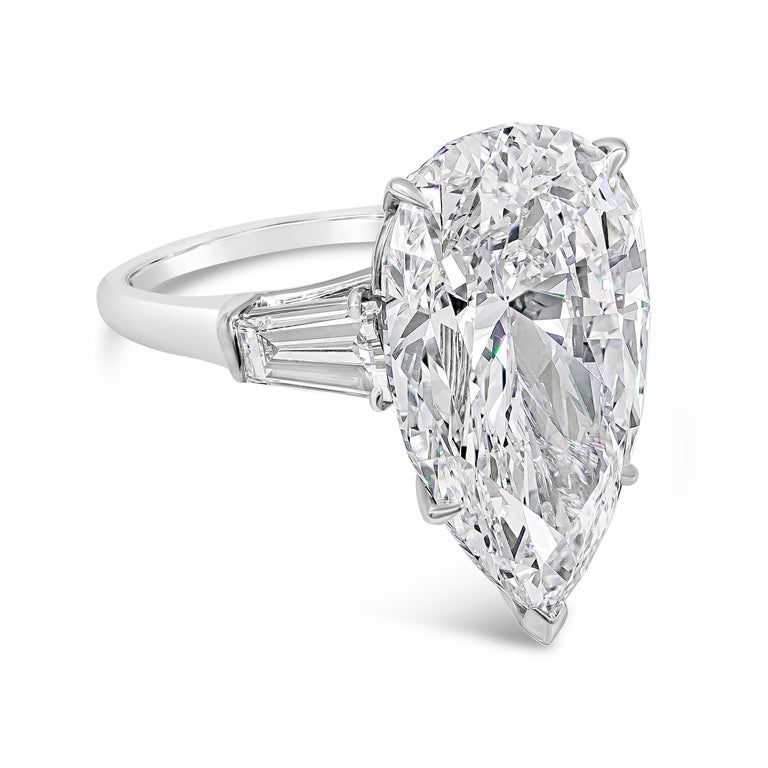 A classic Harry Winston diamond engagement ring showcasing a GIA certified 12.00 carat pear shape diamond, flanked by tapered baguette diamonds weighing 1.35 carats total. The ring is stamped by Jacques Timey which is well-renowned maker of Harry