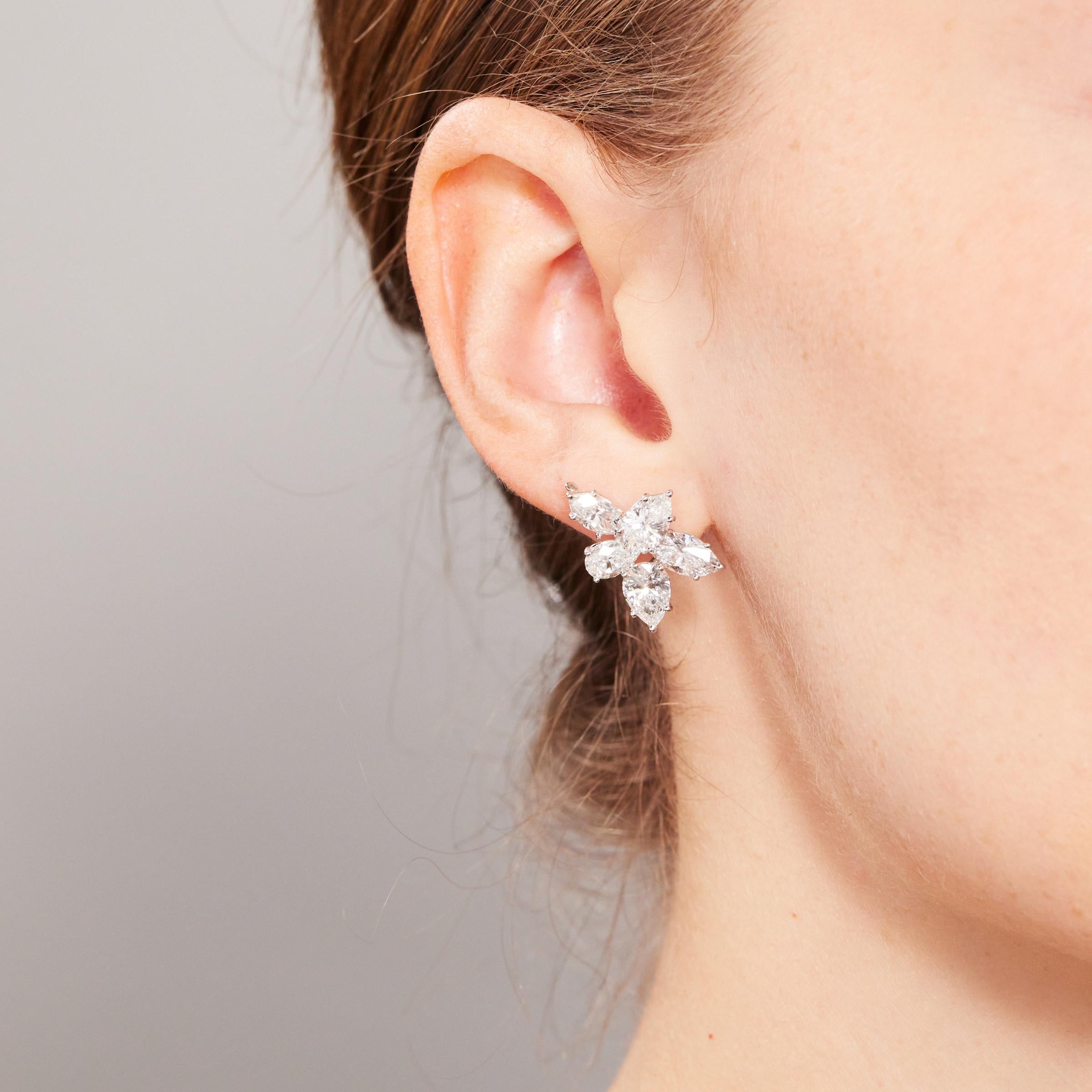 Splendid pair of Harry Winston iconic cluster diamond earrings from 1980s. The earrings showcase an ensemble of 10 glittering diamonds totaling 8 carats and set in platinum with 18 karat gold earring backs. Each earring features 5 diamonds (3 pear