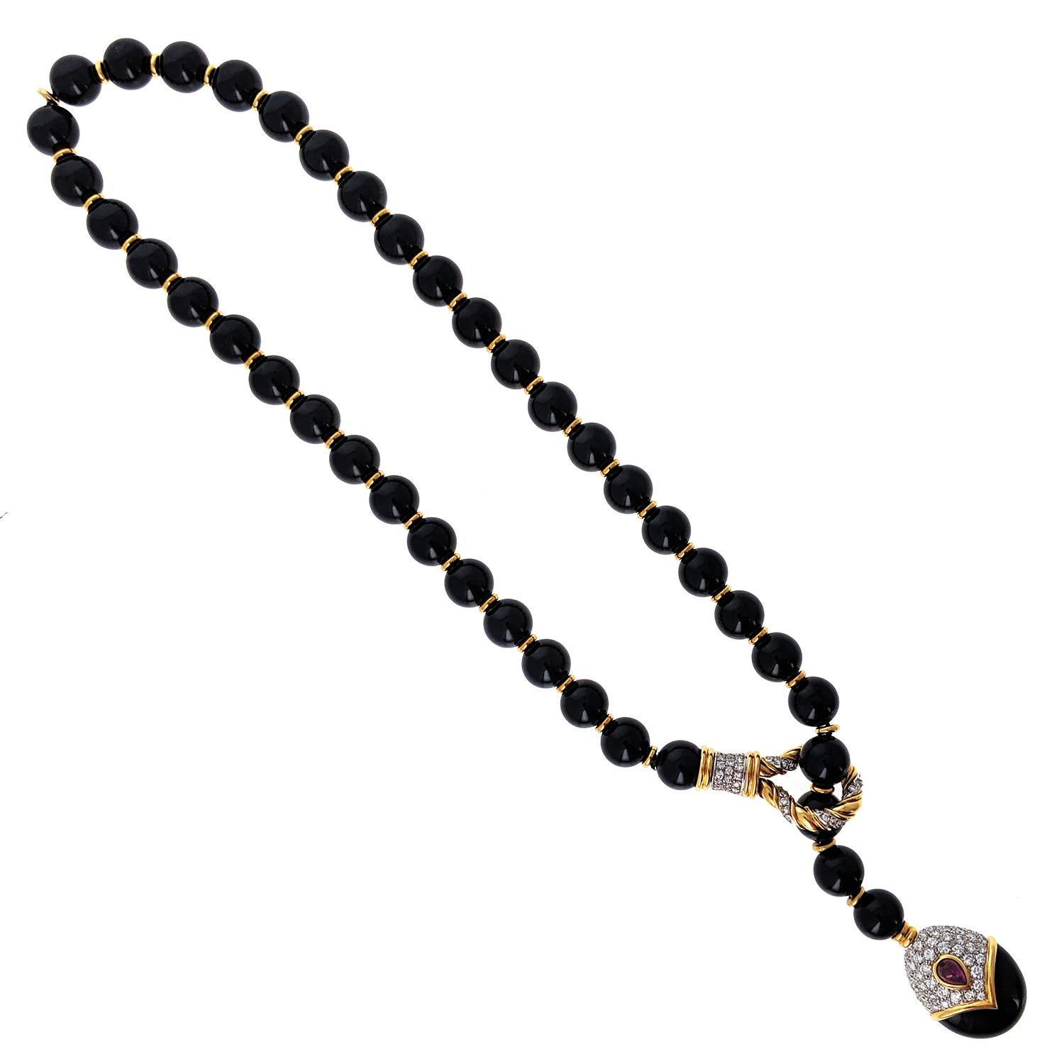 The necklace composed of a row of black jade beads with gold disc spacers, with one side passing through a gold torsade loop set with brilliant-cut diamonds, to the egg-shaped terminal in onyx and diamonds, embellished with a pear-shaped ruby